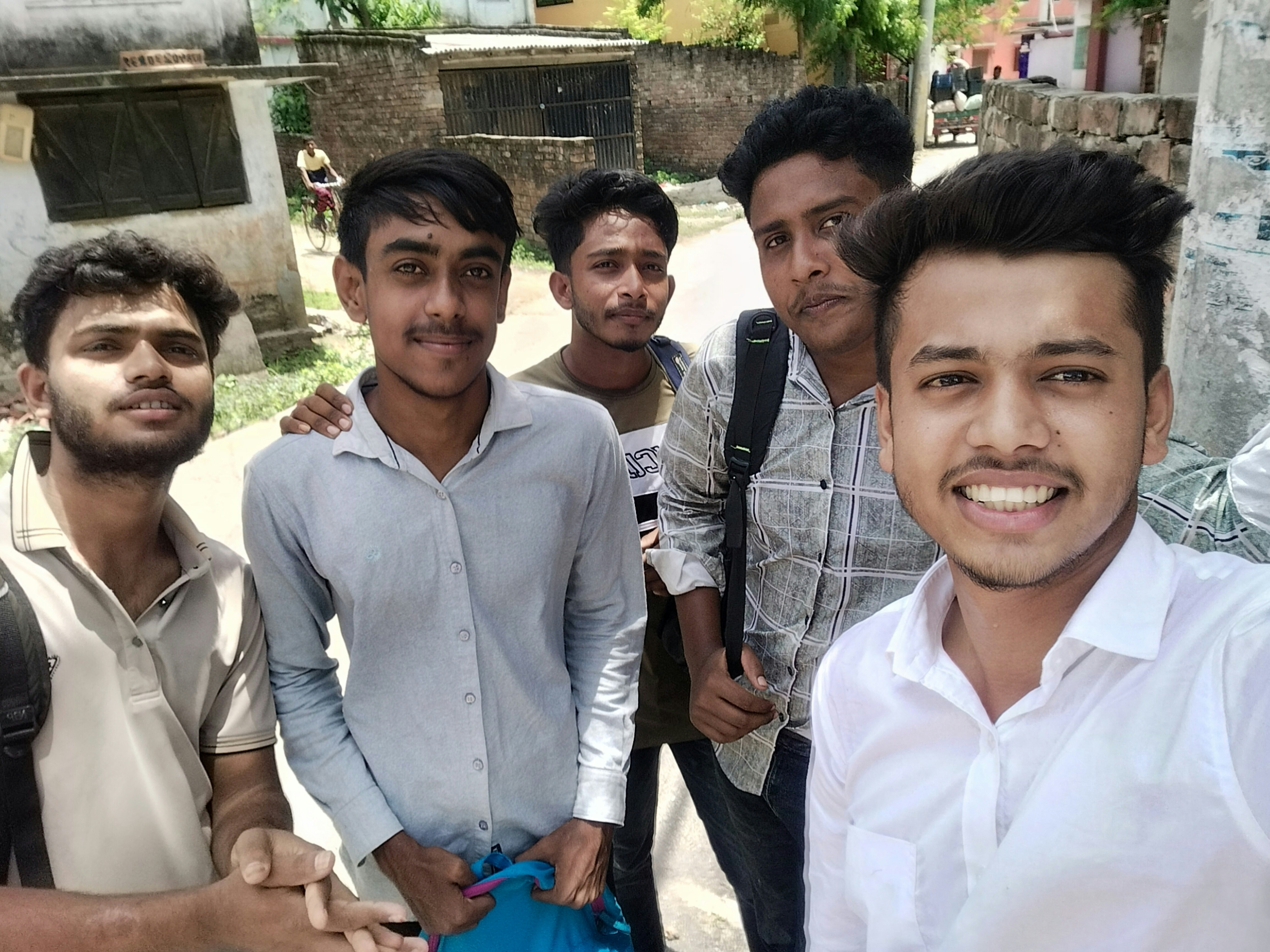 Five young men smiling and posing outdoors.