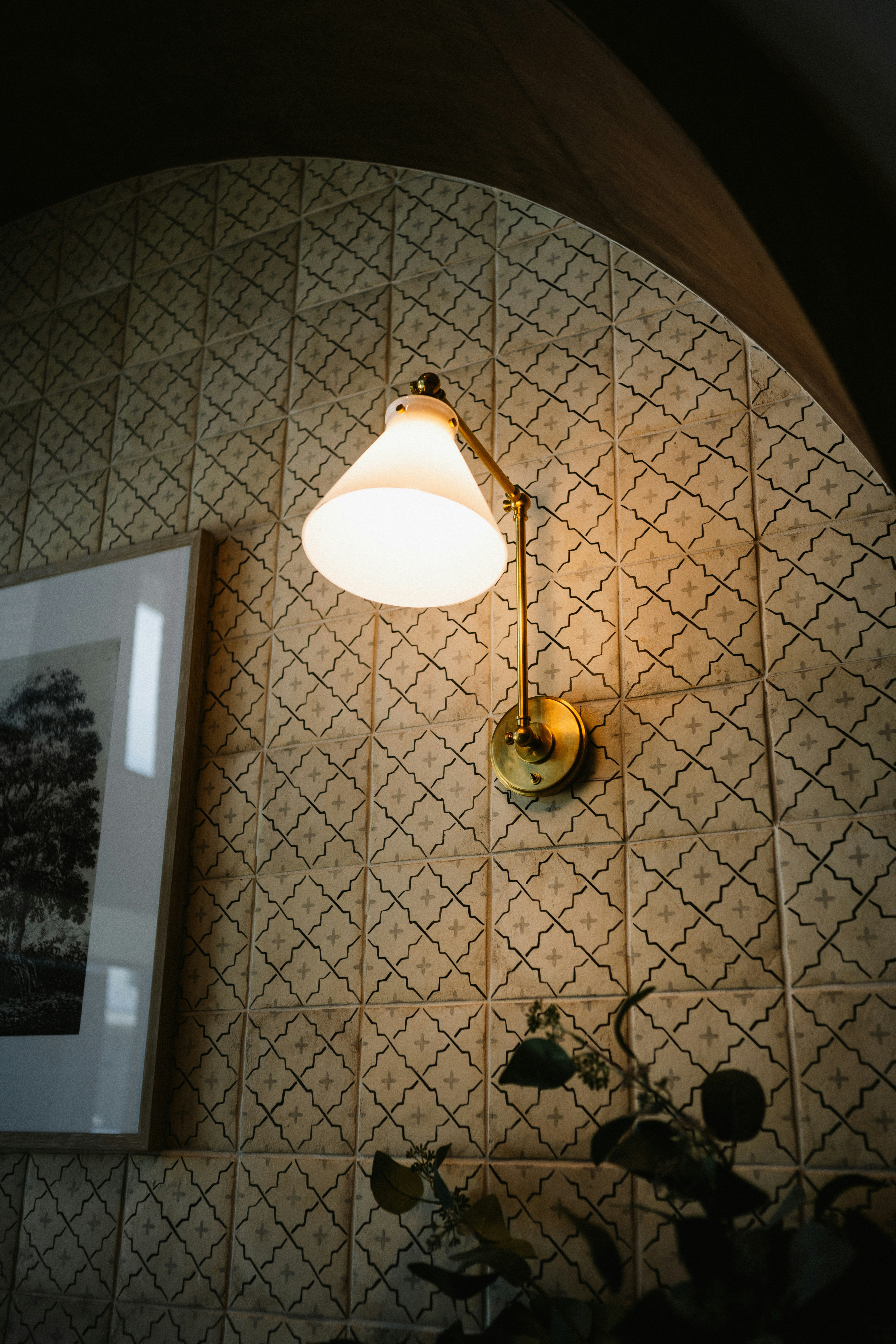 Warm light from a wall lamp on patterned tiles.