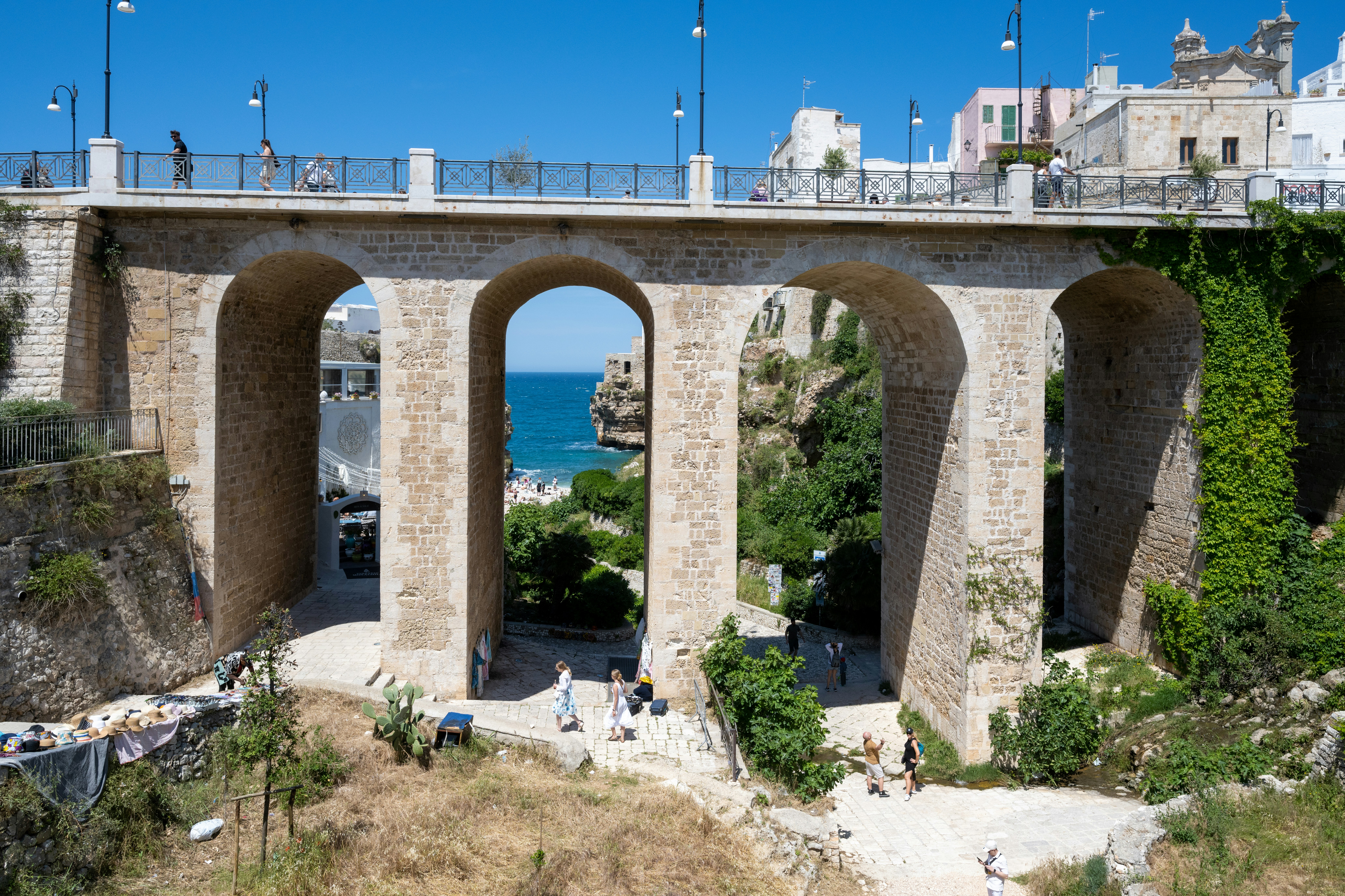Un vecchio ponte di pietra con archi che dà sul mare blu.