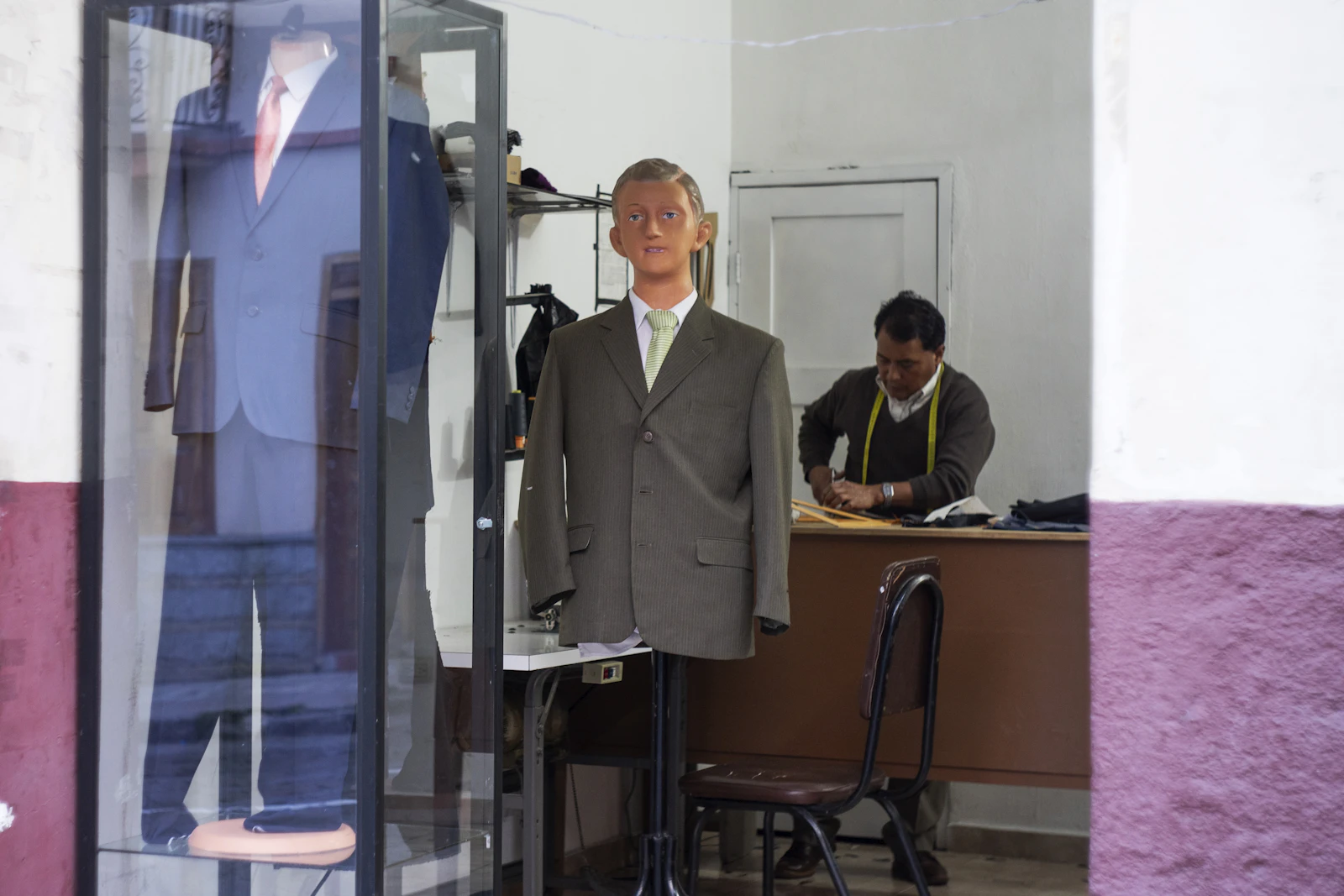 Tailor adjusting a garment on a mannequin in the shop window