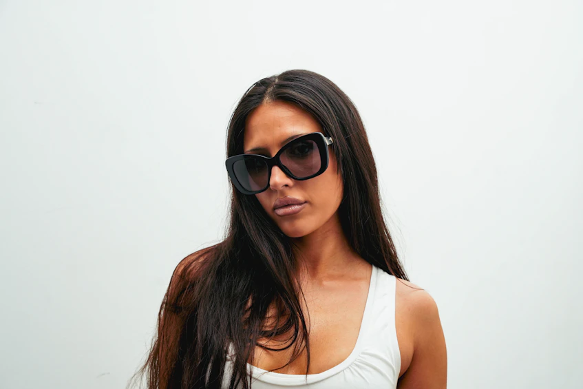 A stylish woman in dark sunglasses and a white top.