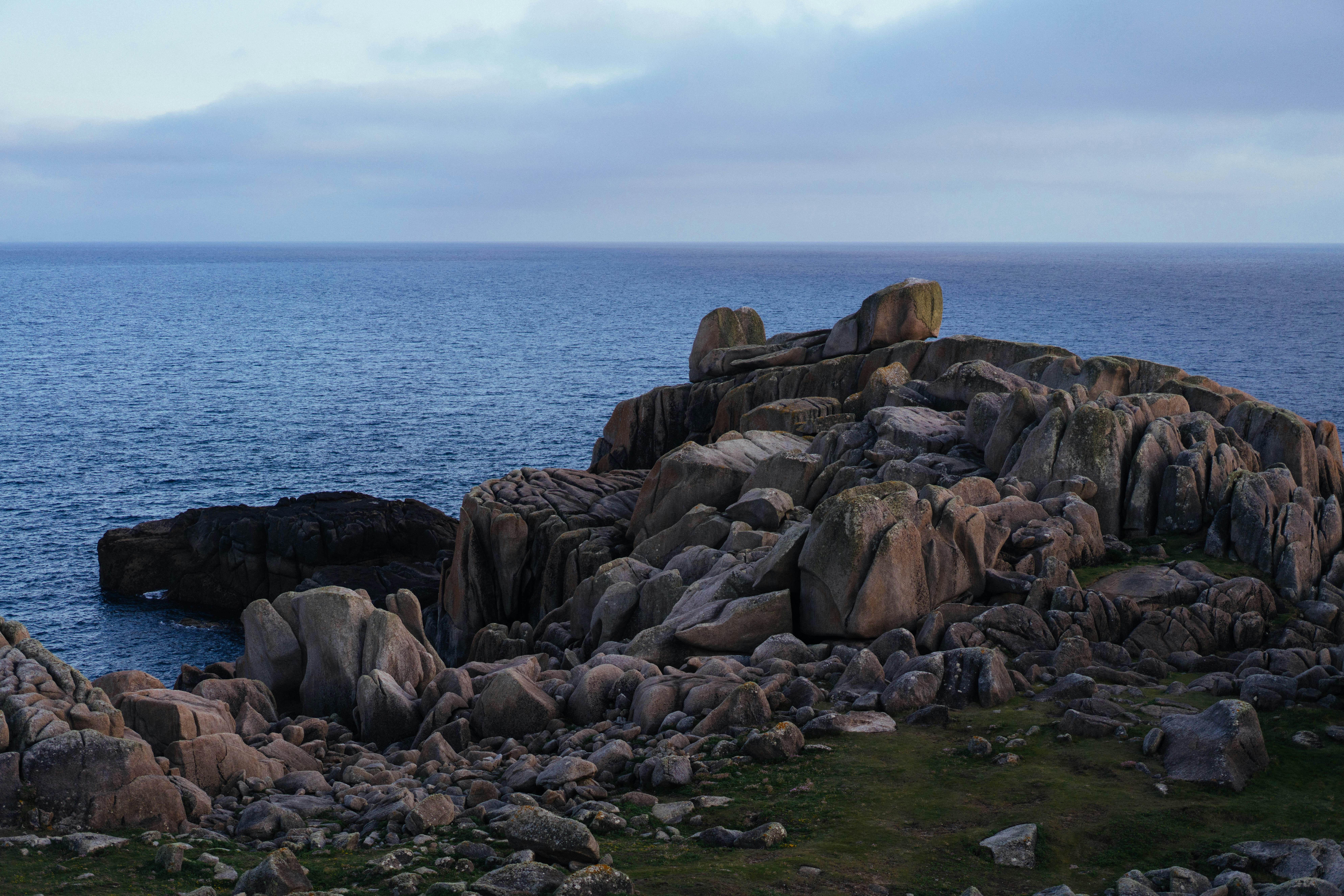 Rocky coastline with ocean and cloudy sky.