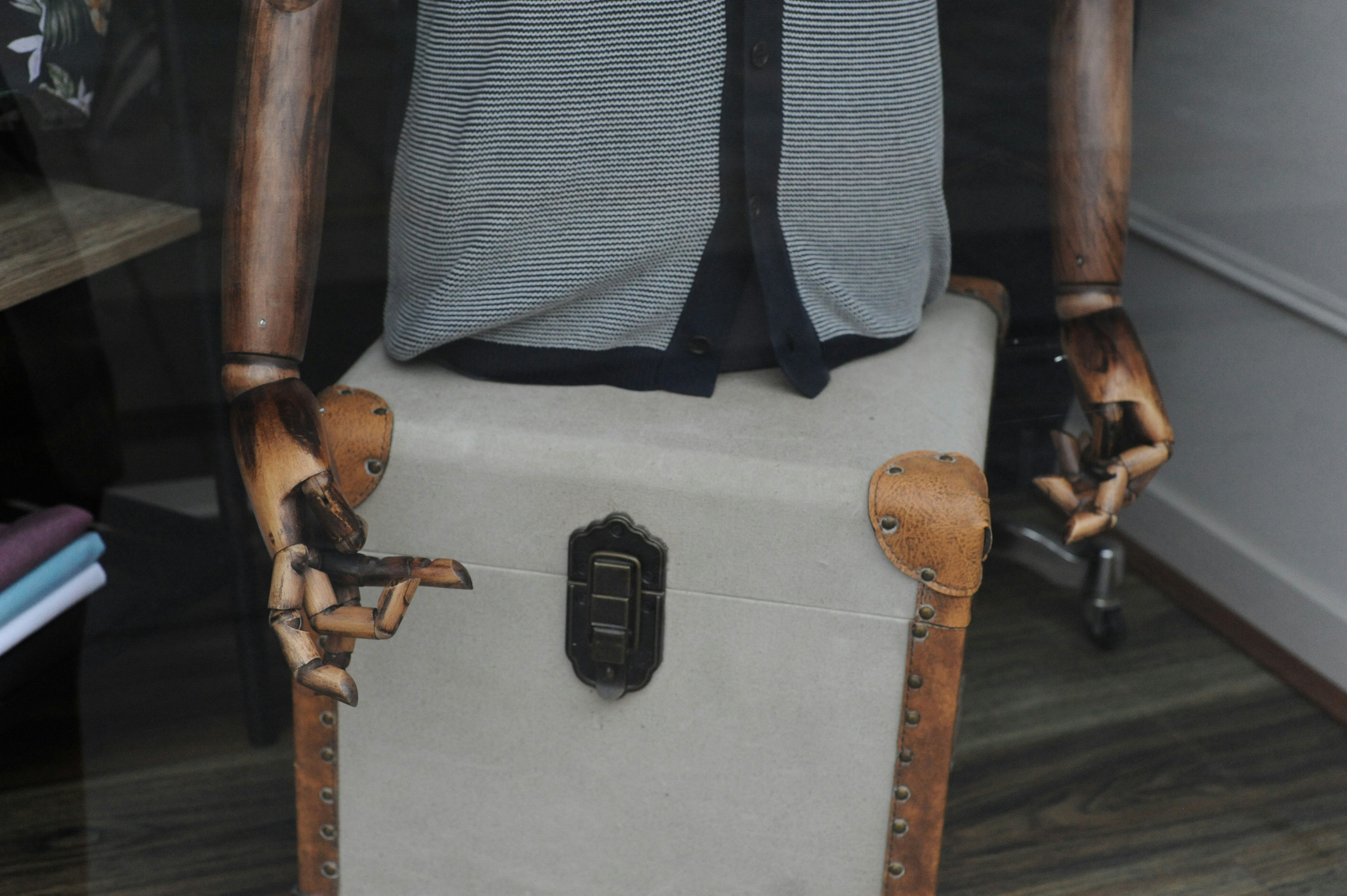 Mannequin torso with wooden arms sitting on a vintage trunk