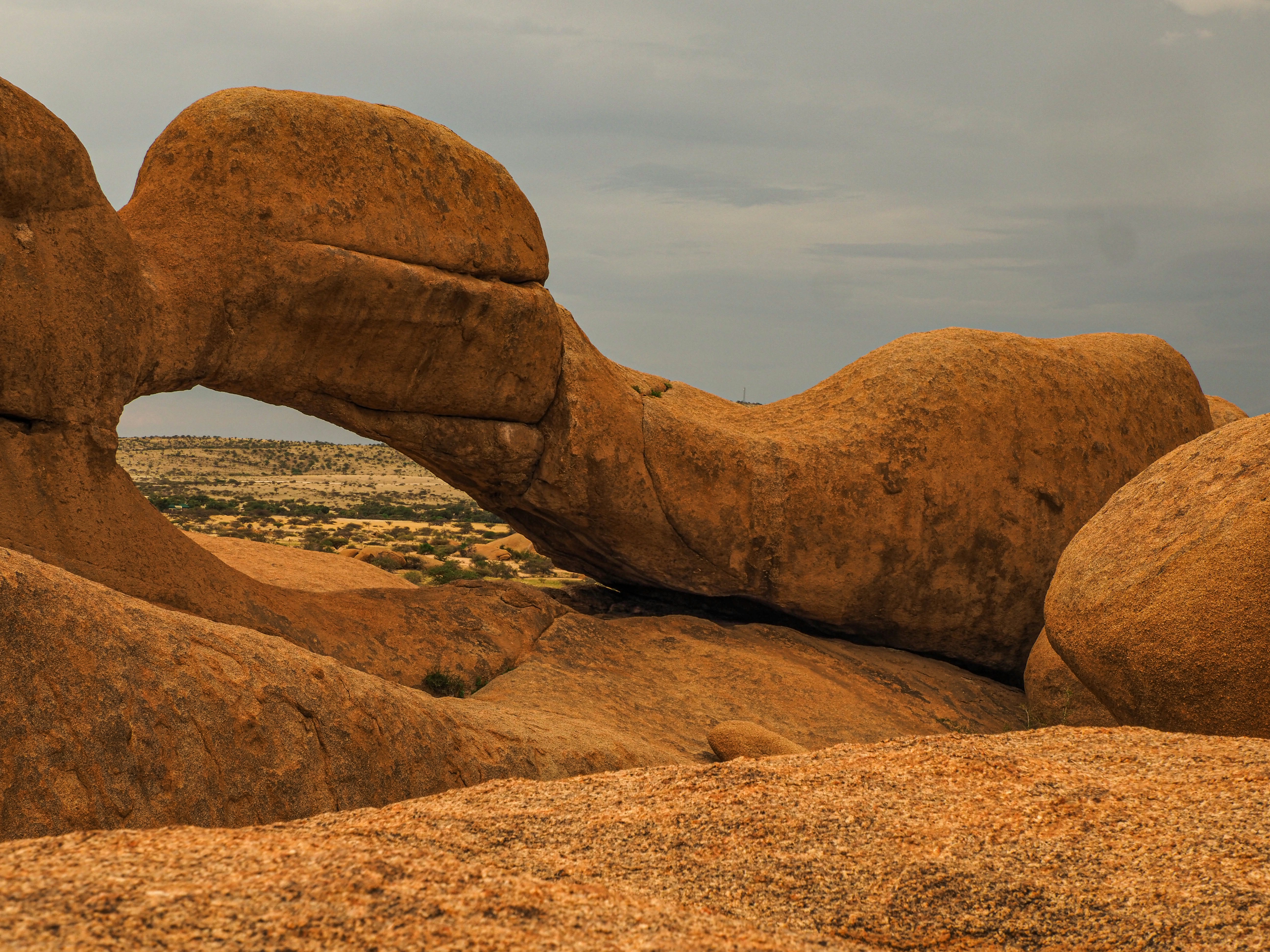 A natural rock arch formation in a desert landscape.