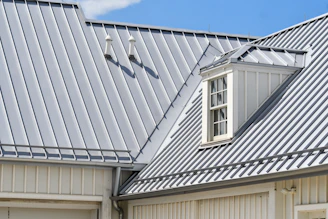 Grey metal roof, white siding, and a dormer window