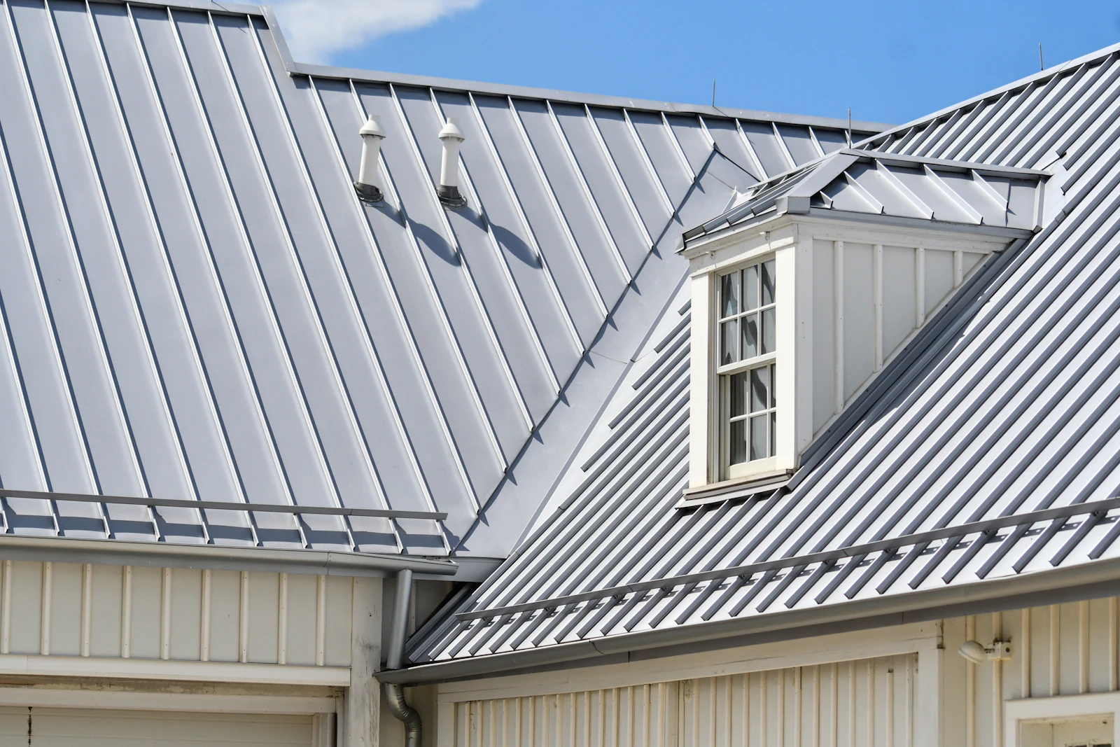 Gray metal roof with white siding and a dormer window