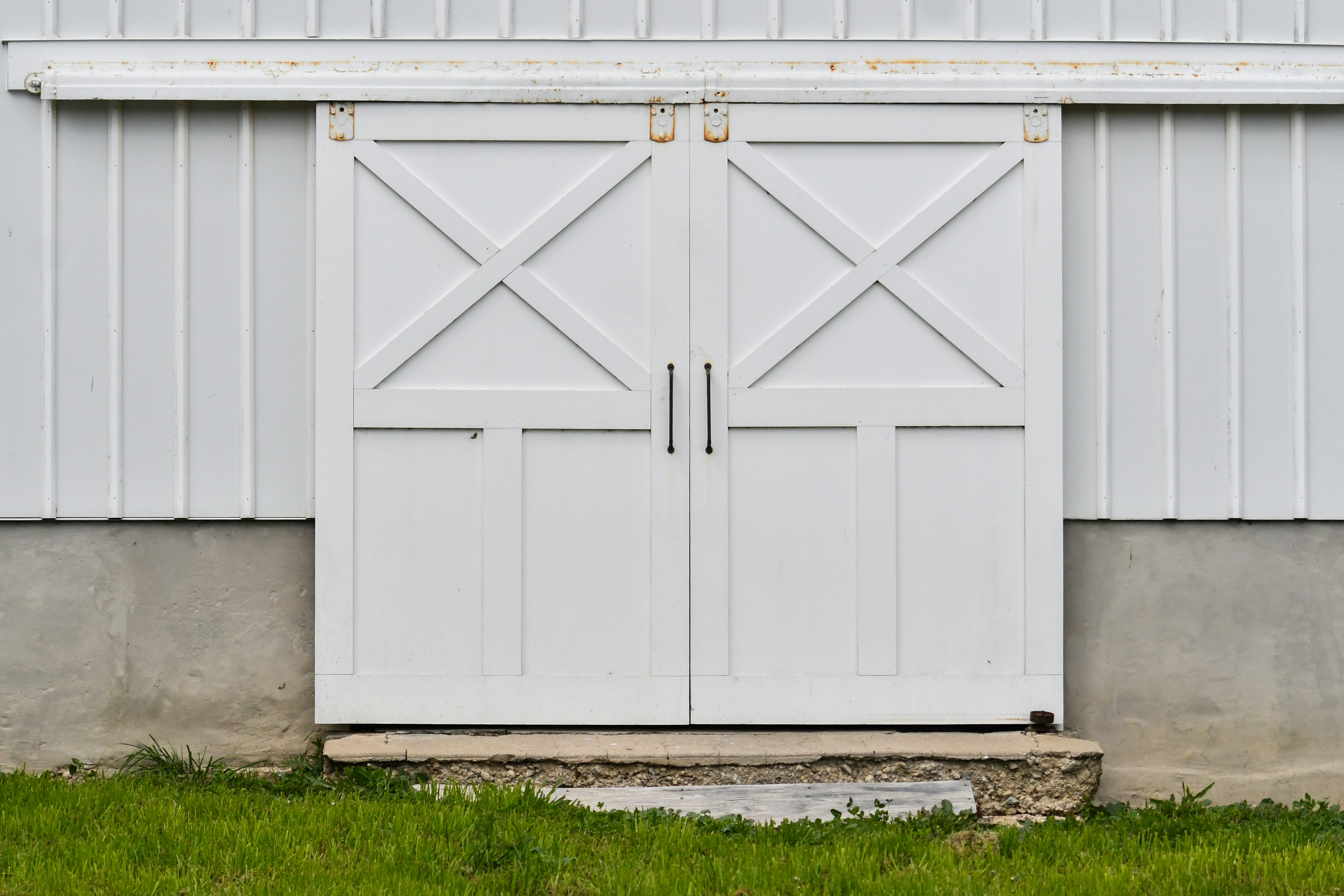 Portes de grange blanches fermées avec un motif en X sur un bâtiment.