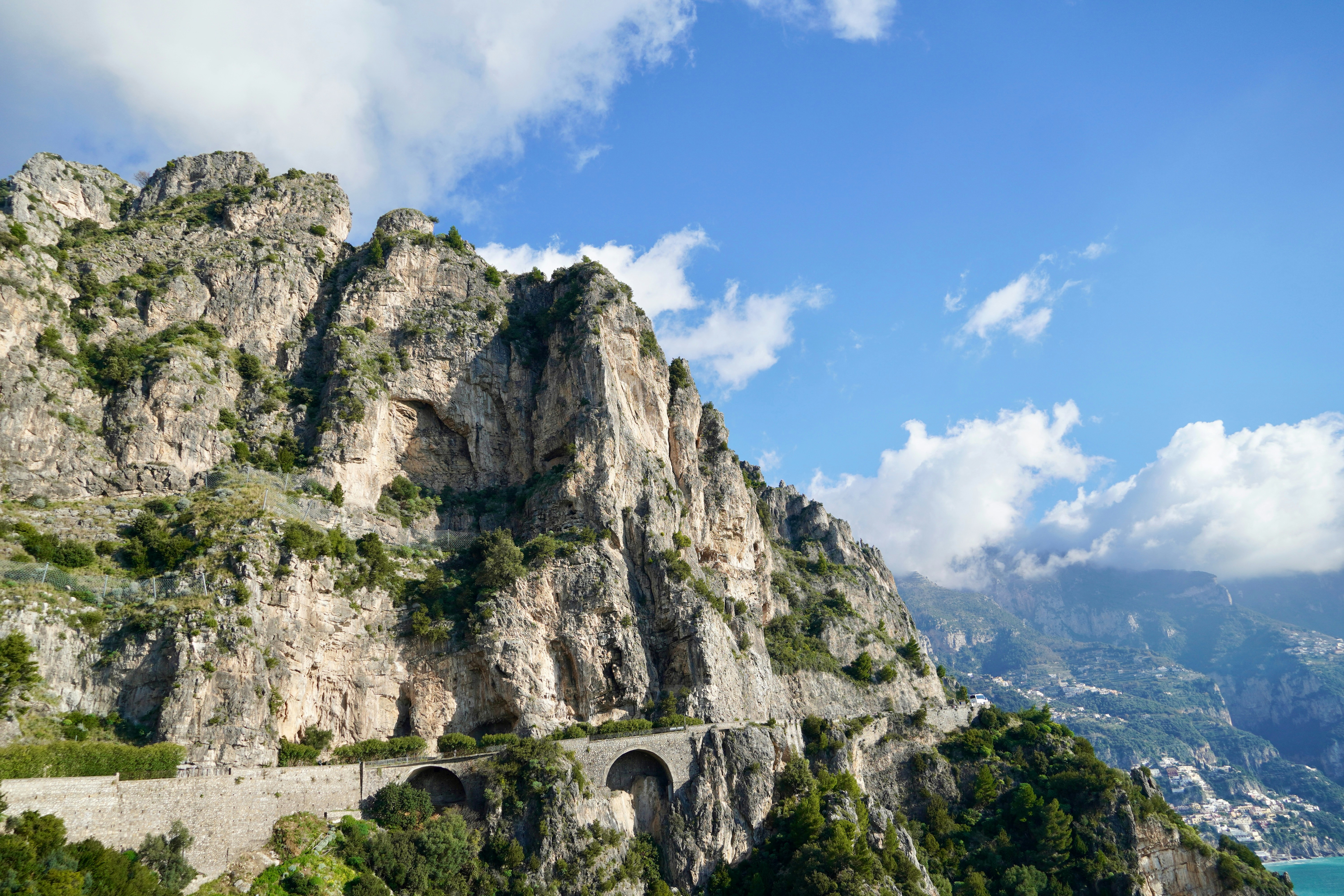 Strada costiera tortuosa costruita in montagne aspre sotto un cielo azzurro.
