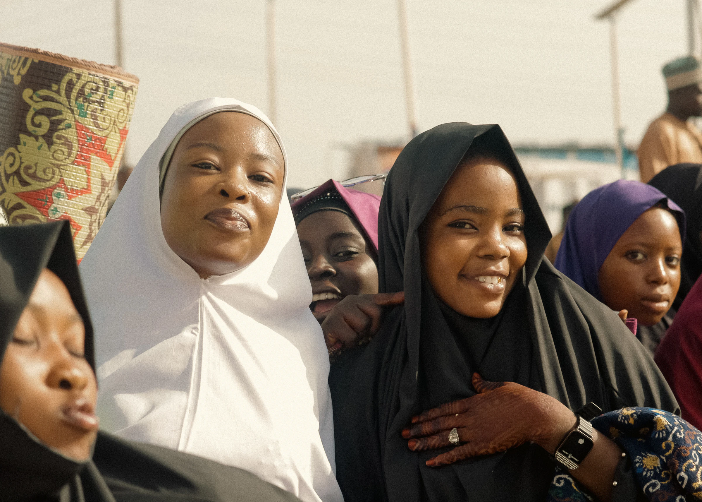 Smiling women in hijabs gathered together.