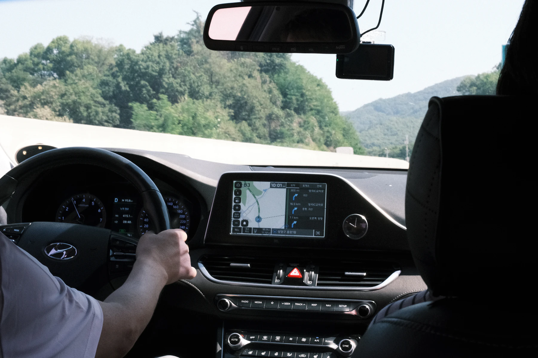 Driver using a modern dashboard navigation system with the road visible ahead