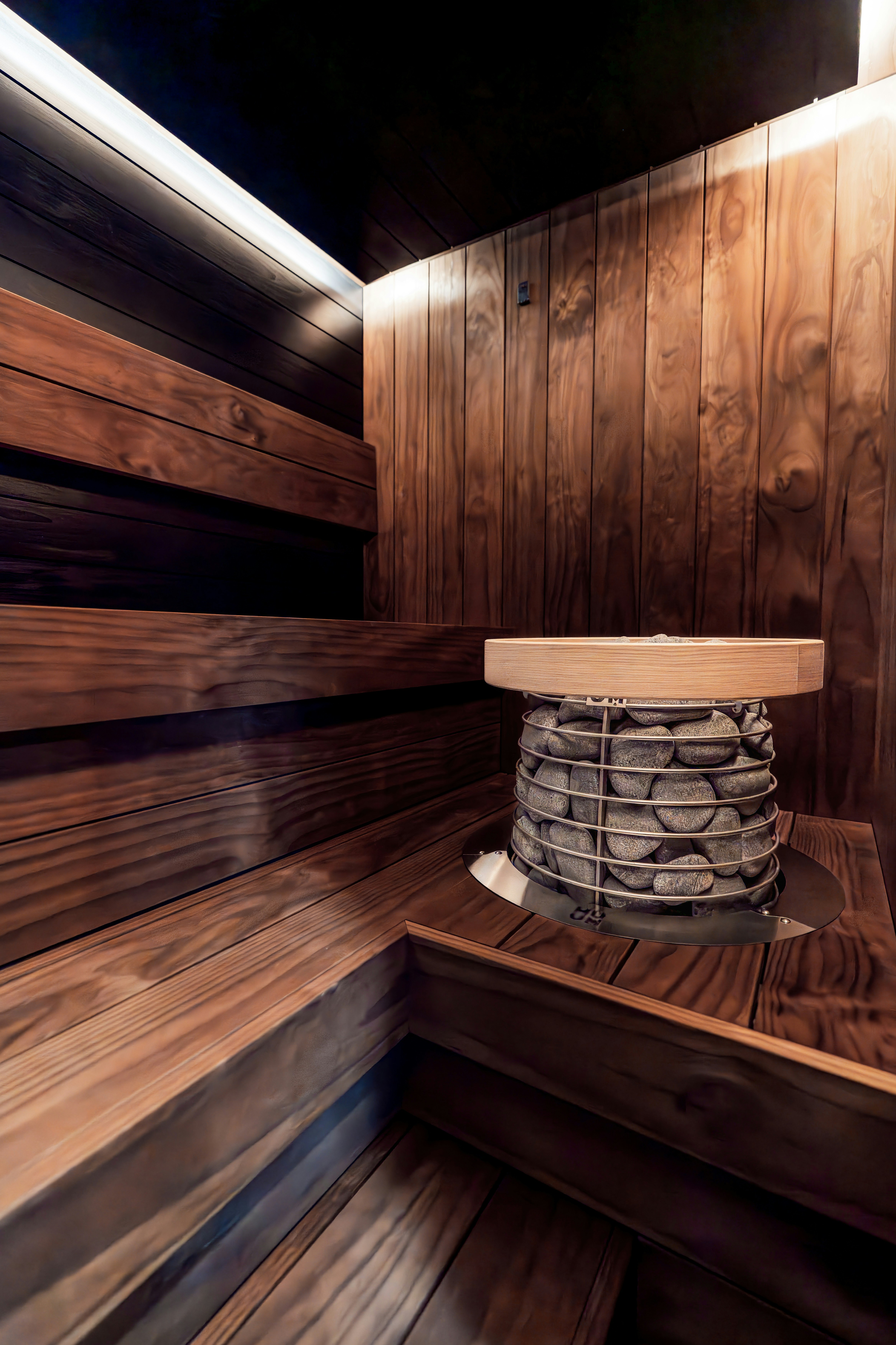 Intérieur moderne de sauna avec bancs en bois et chauffage en pierre.