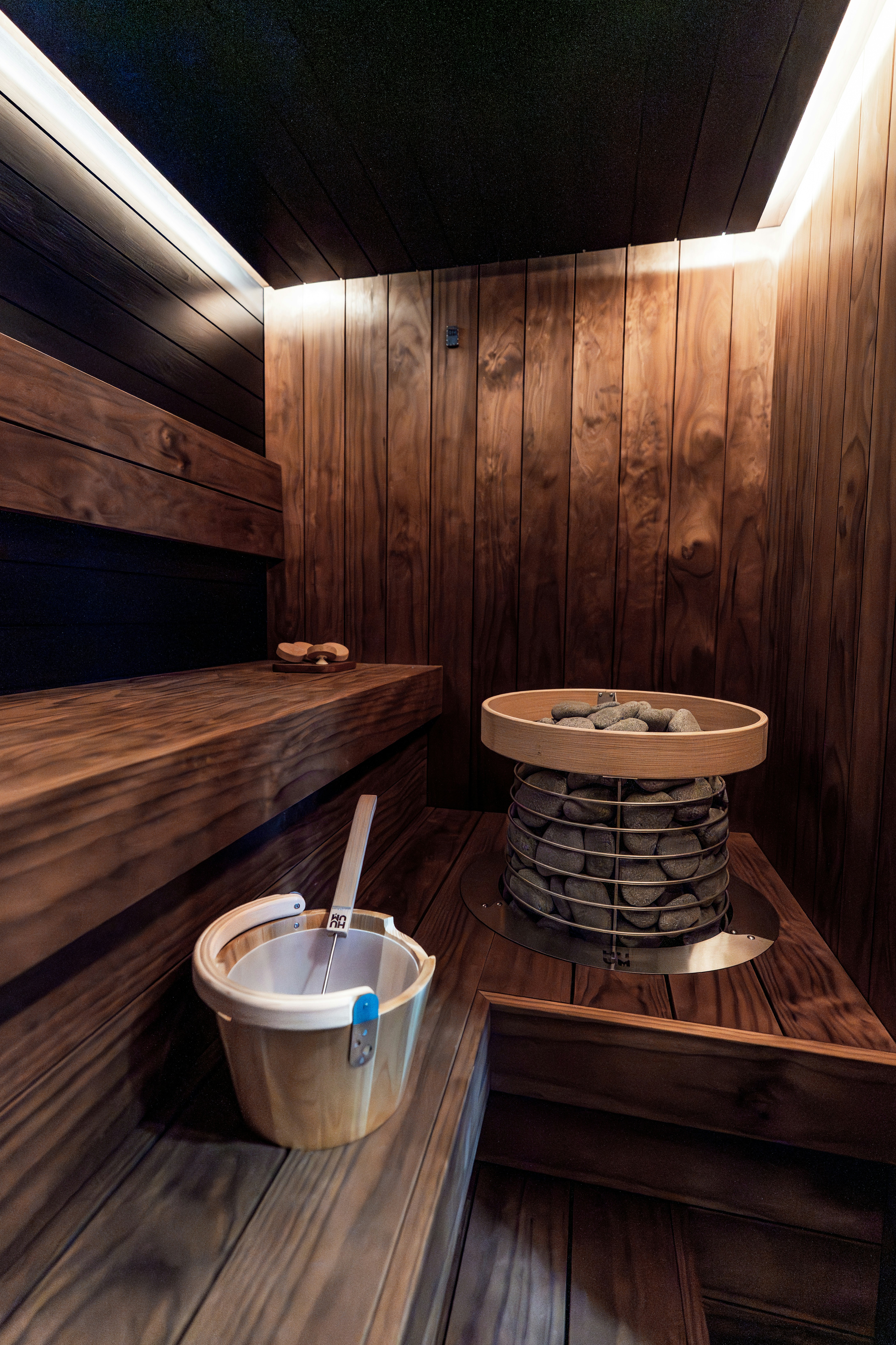 Un sauna en bois traditionnel avec bancs, chauffage et seau.