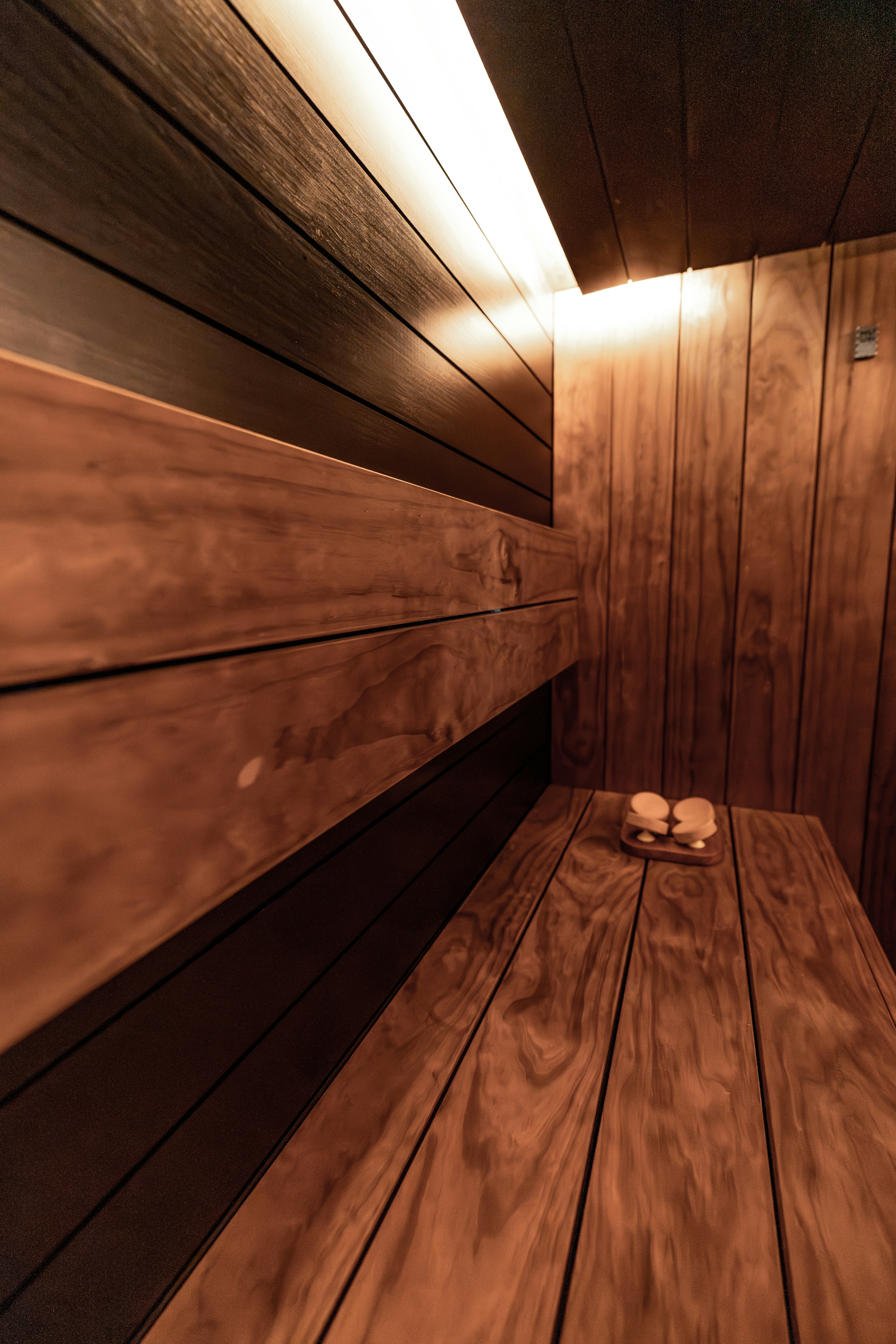 Intérieur en bois de sauna avec bancs et éclairage chaleureux.