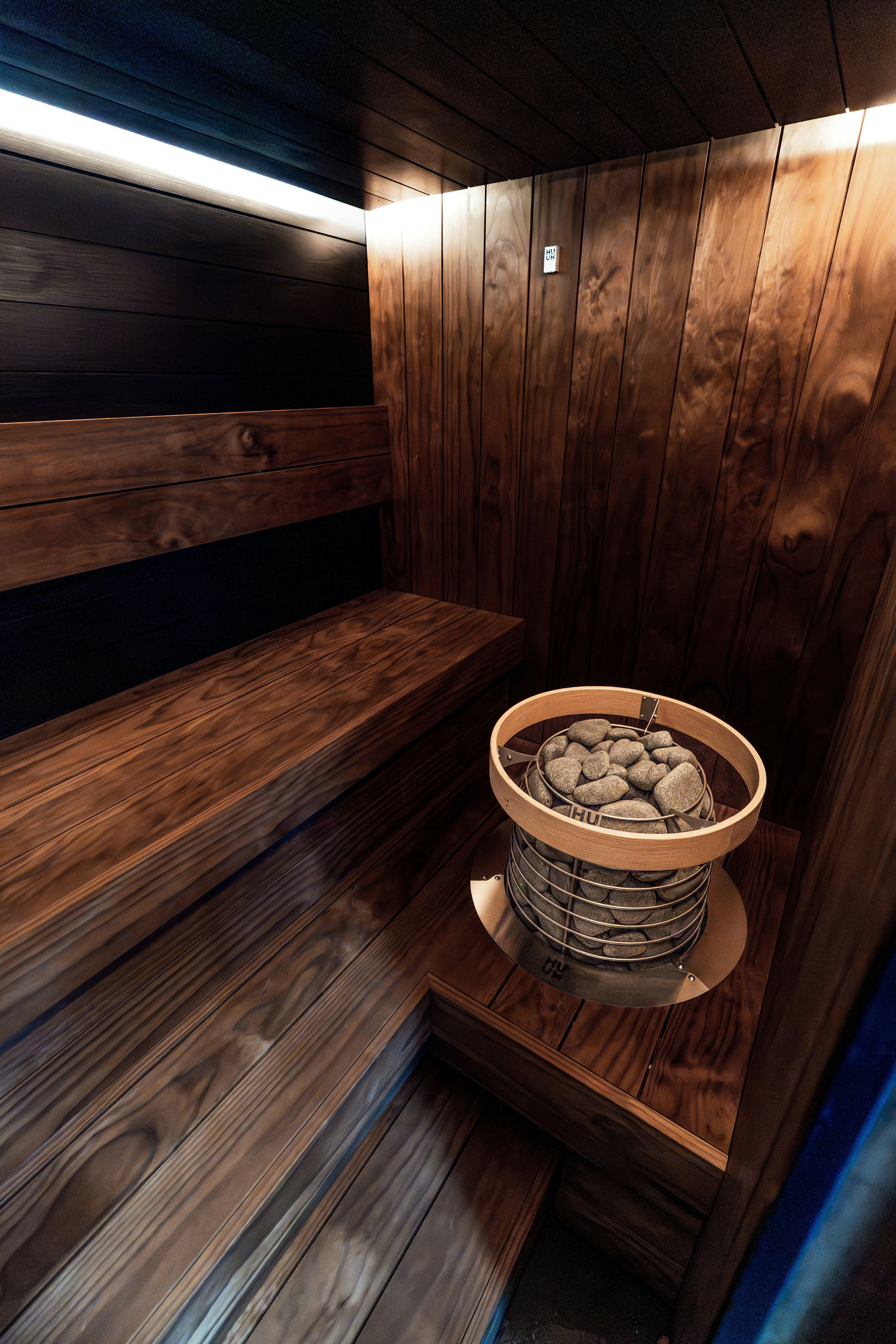 Intérieur chaleureux de sauna en bois avec bancs et chauffage en pierre.
