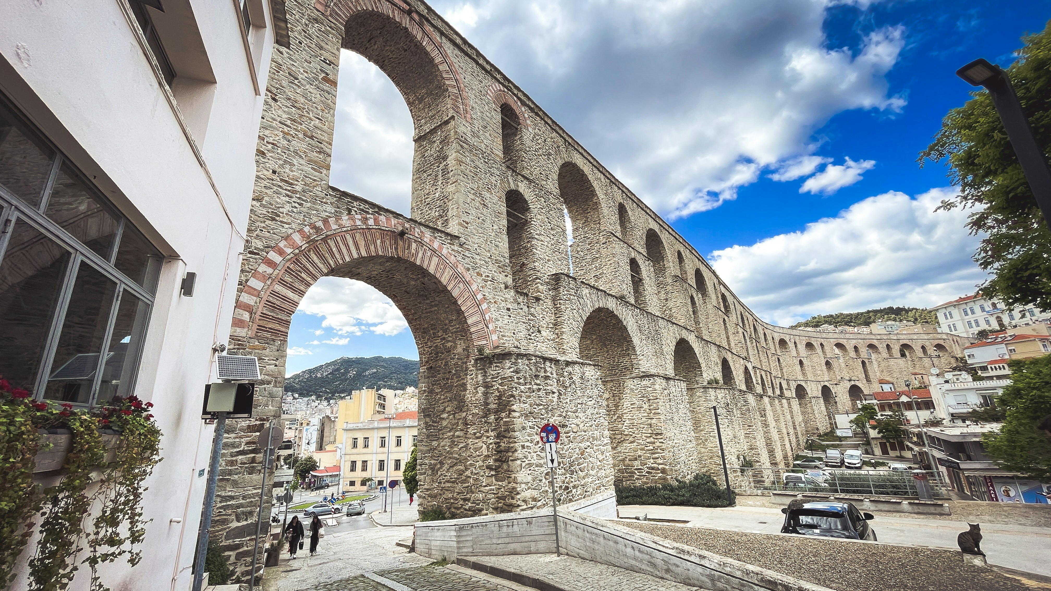 Arcos históricos de aqueduto de pedra sobre uma rua da cidade.