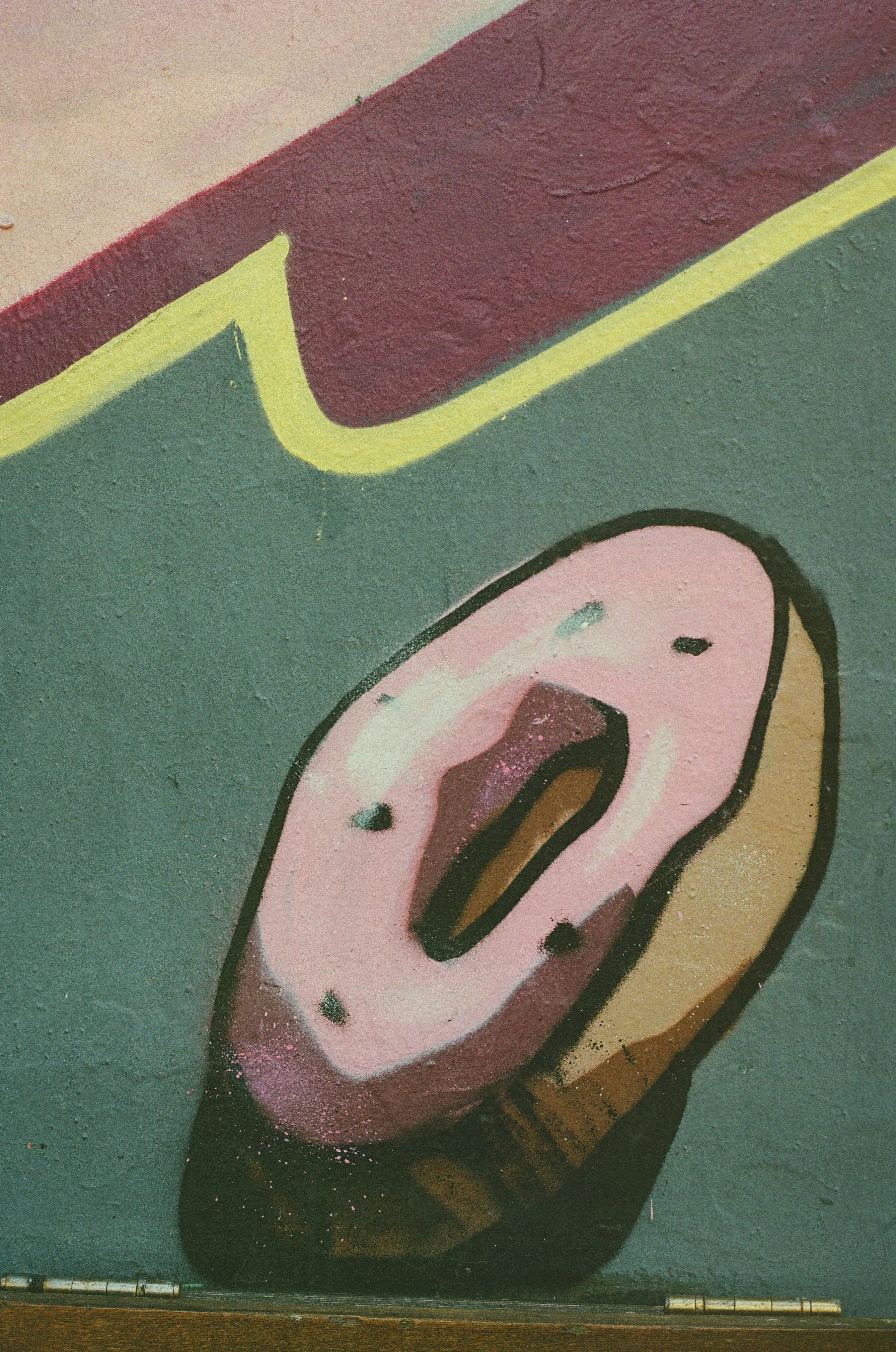 A cartoon donut with pink icing painted on a wall.
