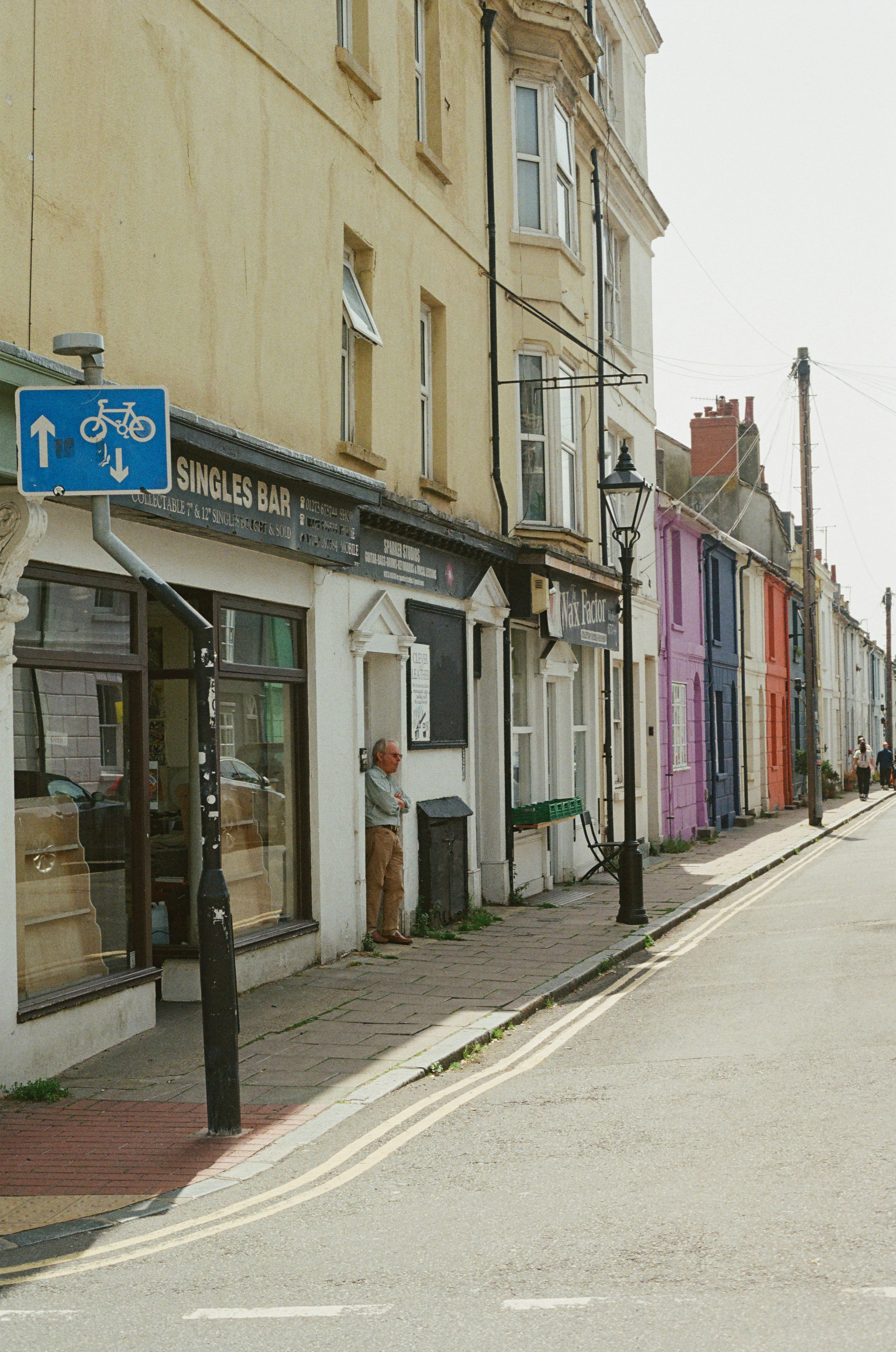 A person stands outside shops on a colorful street.