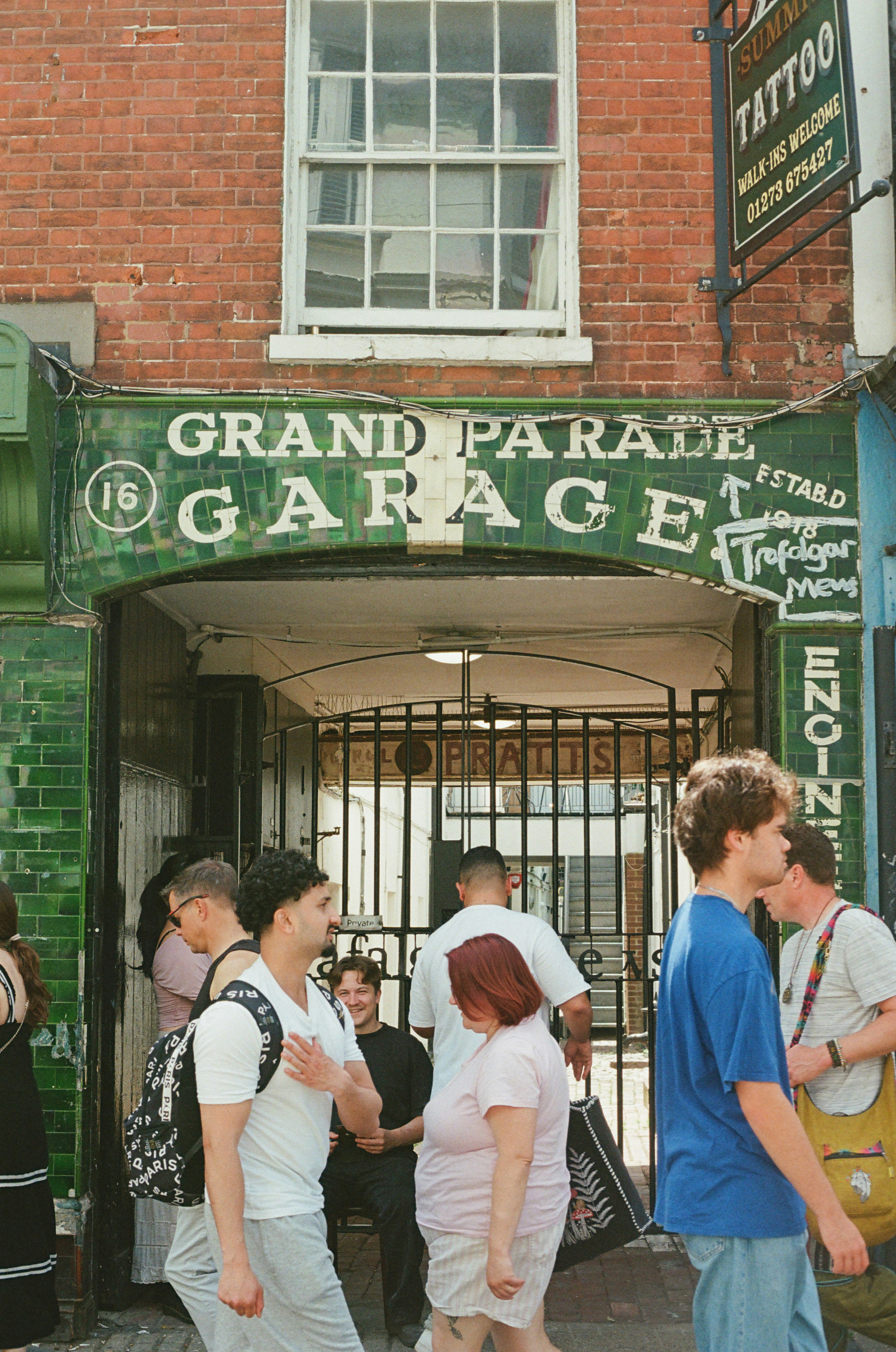 People walking past an old grand parade garage entrance.
