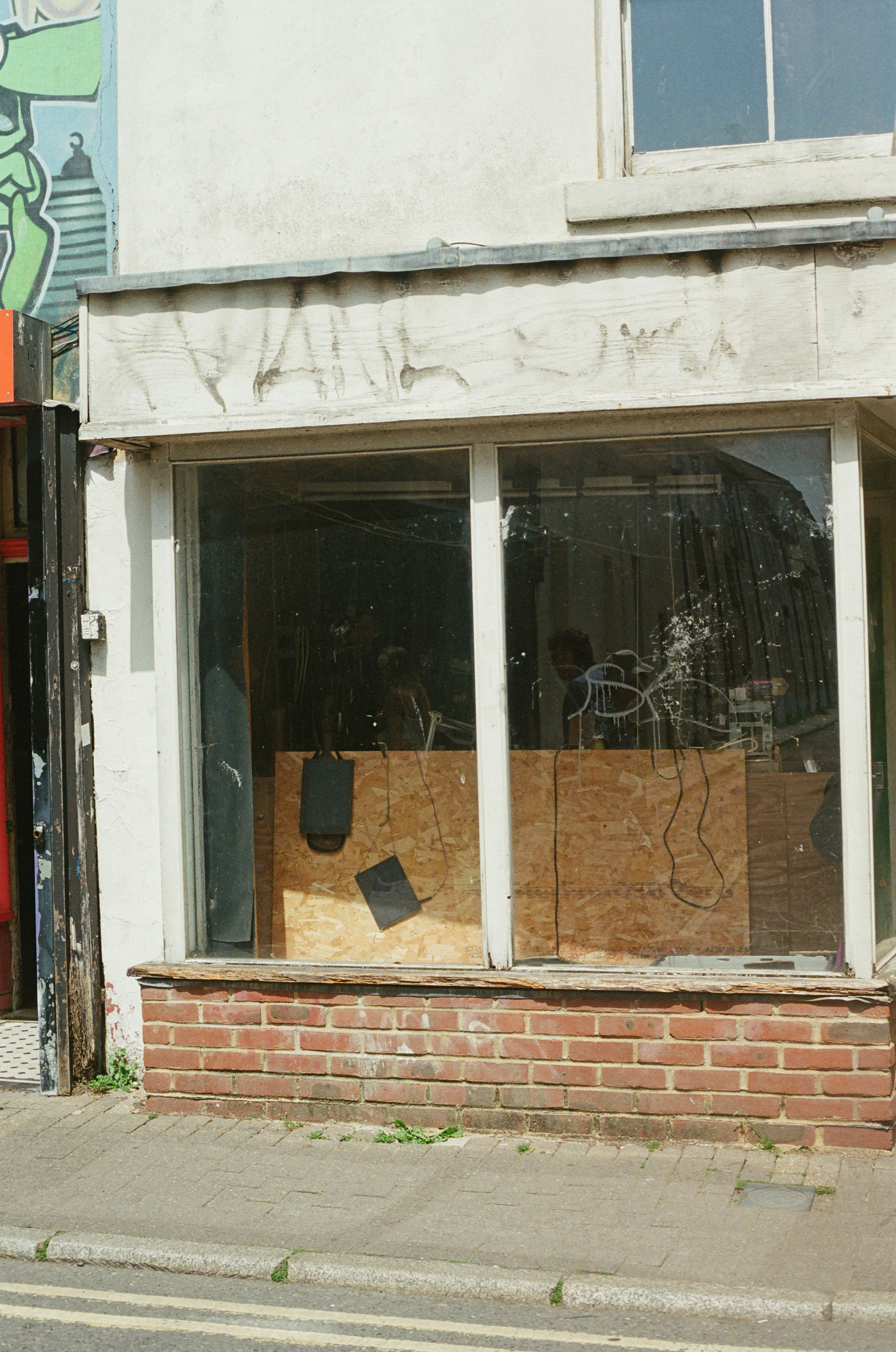 An abandoned storefront with boarded-up windows and a brick base.