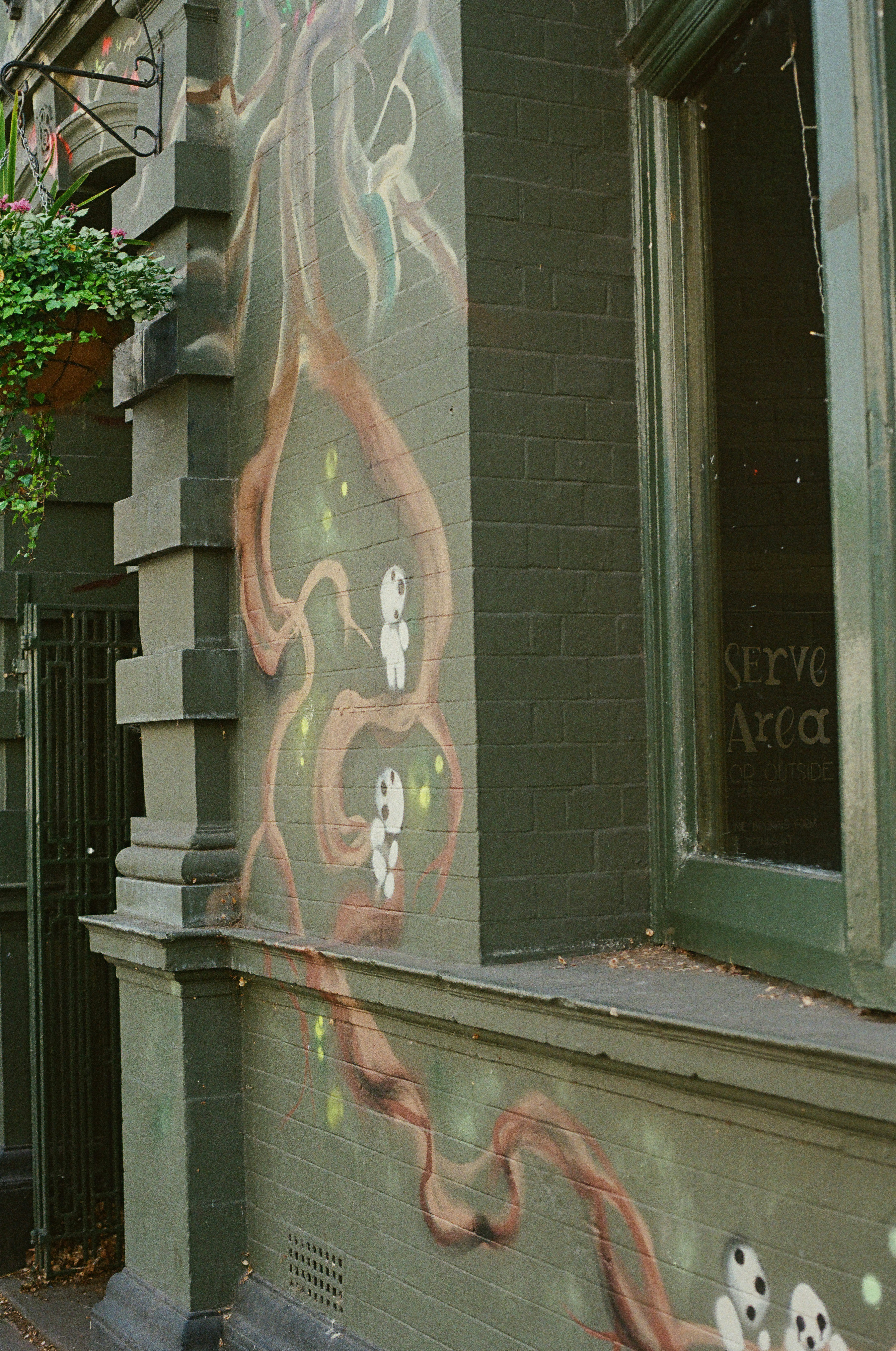 Mural on a building wall featuring roots and ghost-like figures.