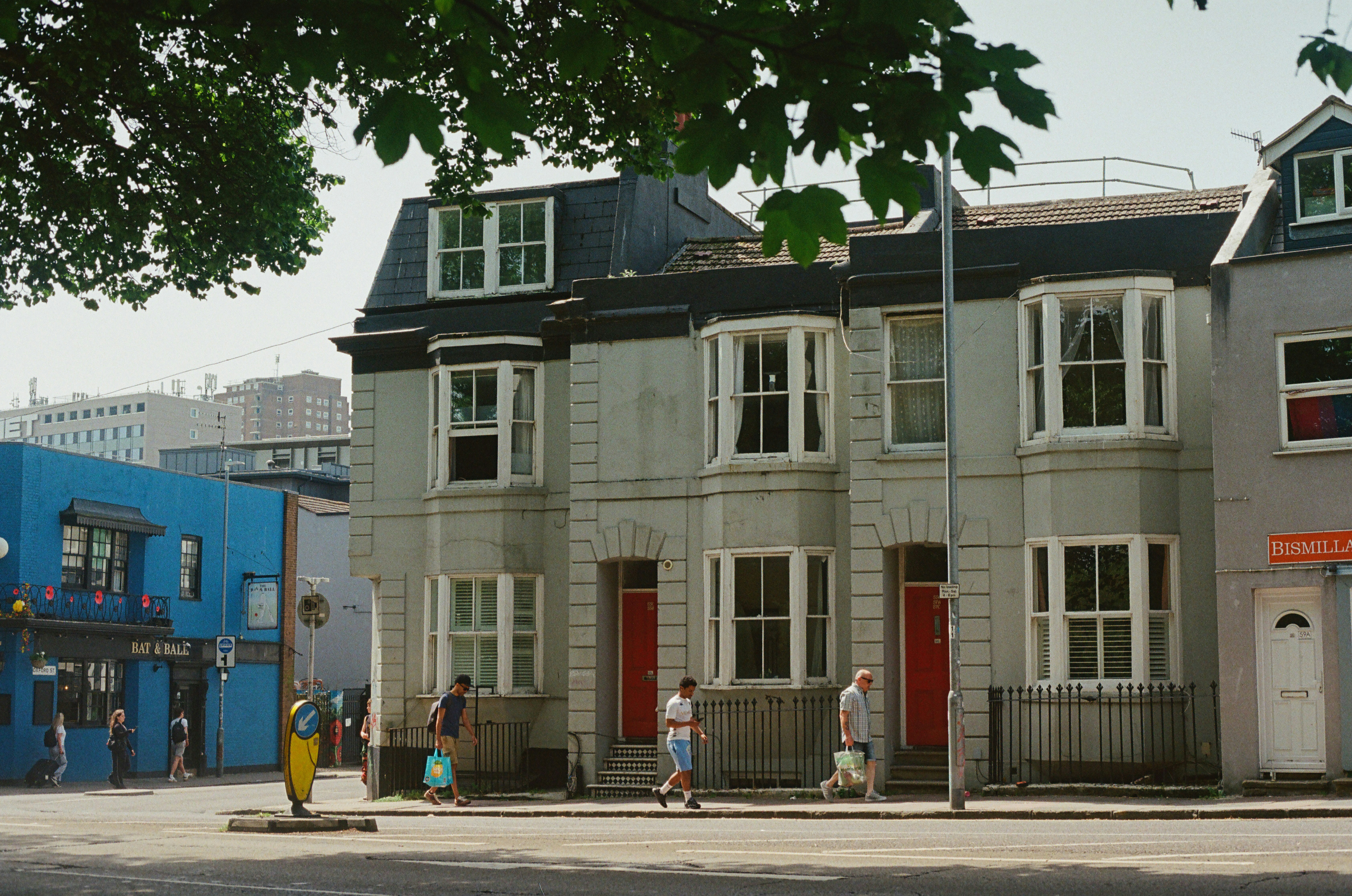 Grey terraced houses with red doors on a sunny street.