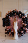 Woman in white dress with 18th birthday balloons.