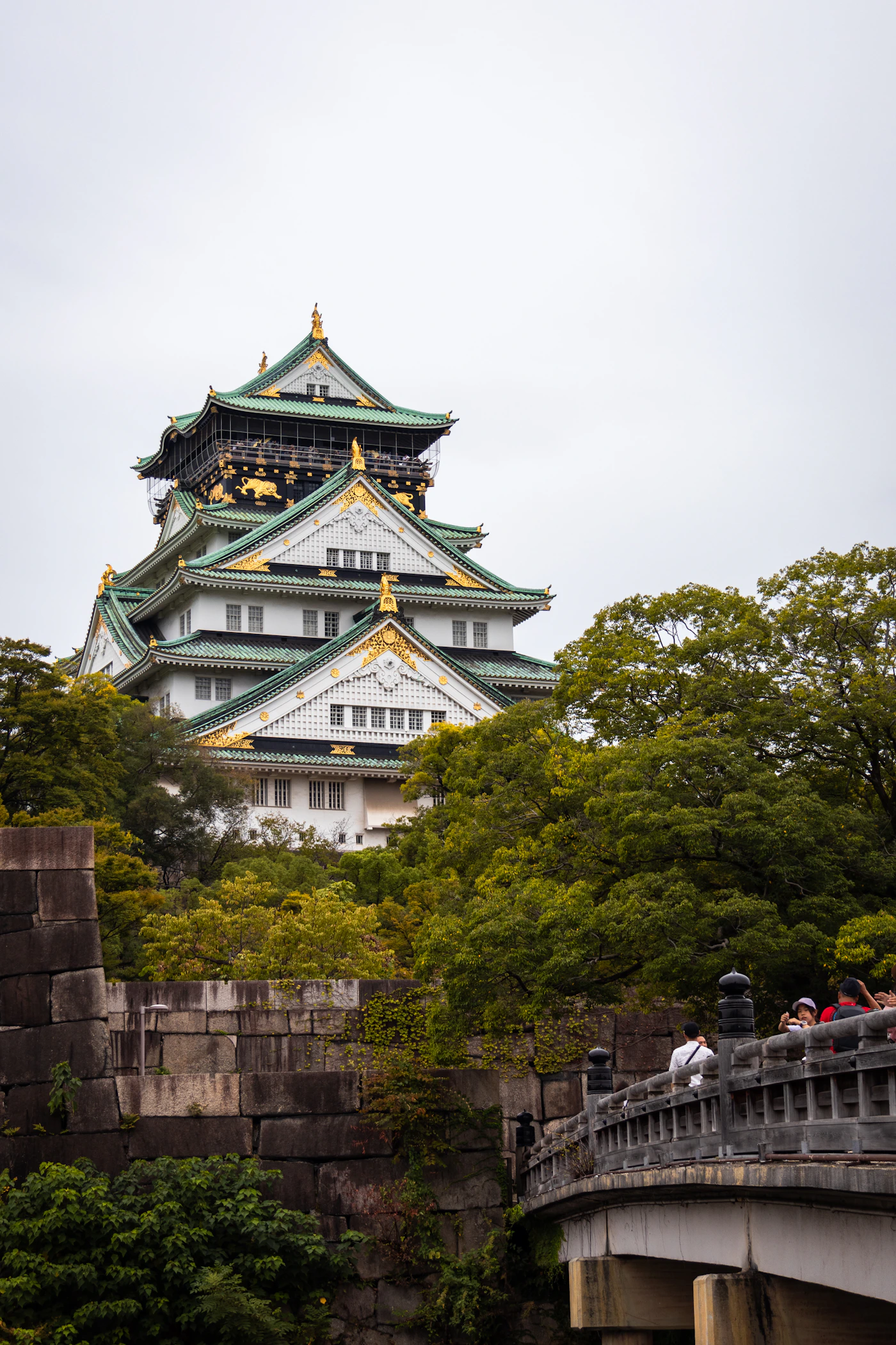 Osaka Castle rising above lush trees and historic stone walls, Japan