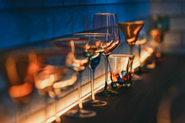 Empty colorful glass cups and goblets illuminated by warm light.