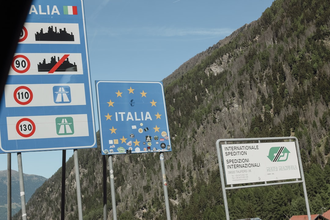 Road signs for italy and eu at a mountain border.