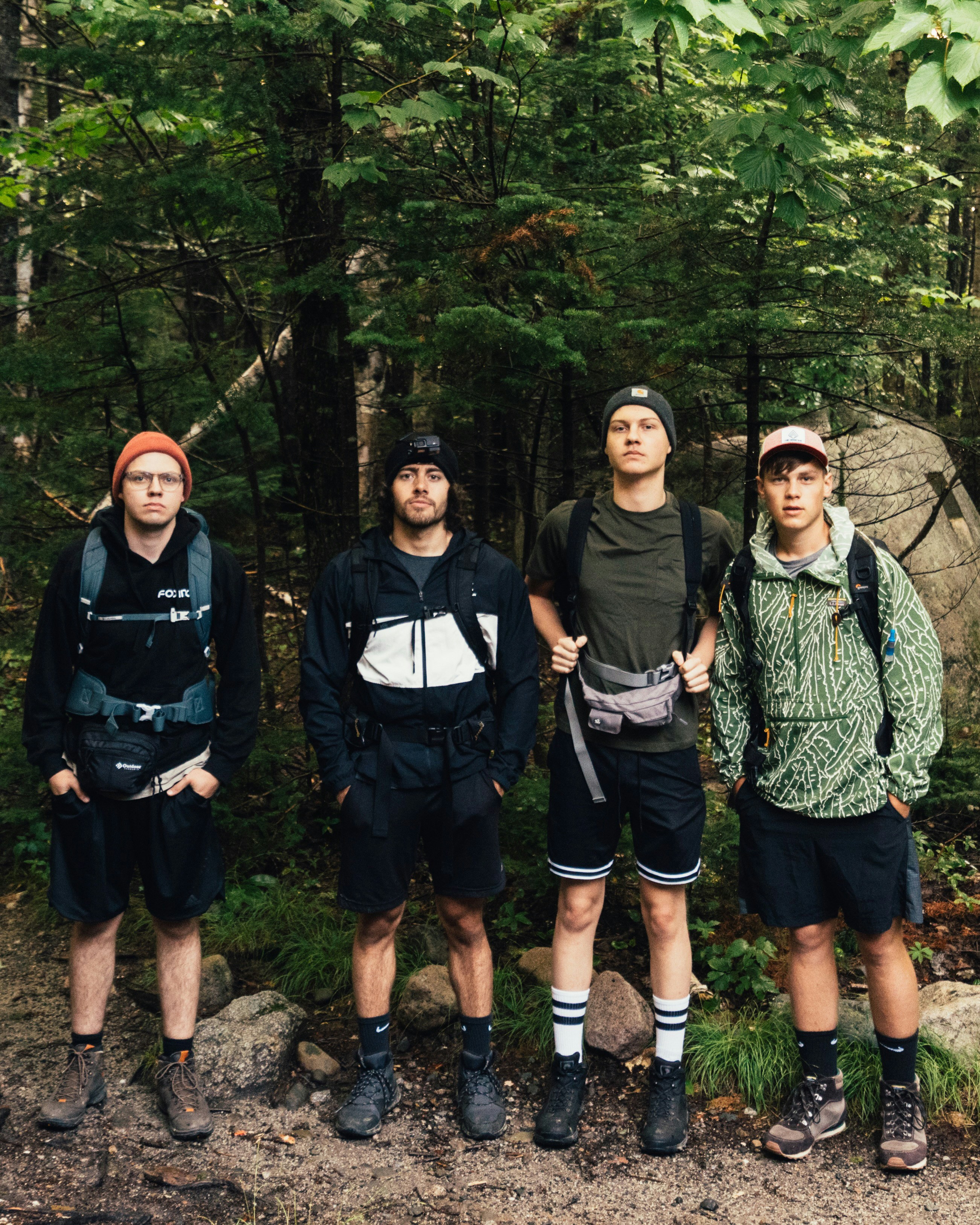 Four men in hiking gear standing in a lush forest.