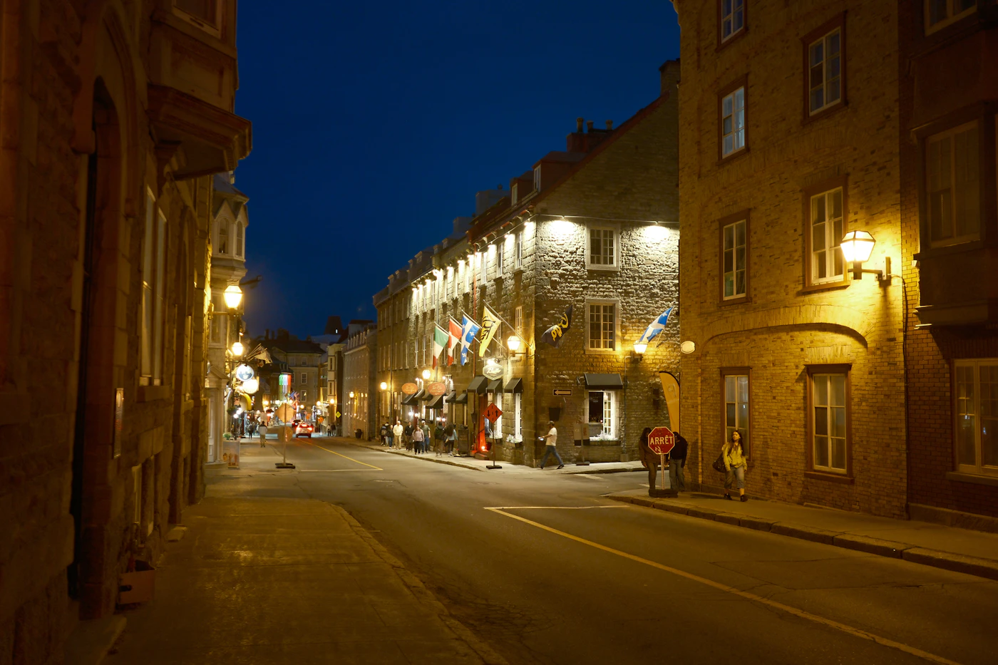 Quiet Old Quebec City street at twilight with stone buildings and warm street lighting creating the specific evening atmosphere of the historic district