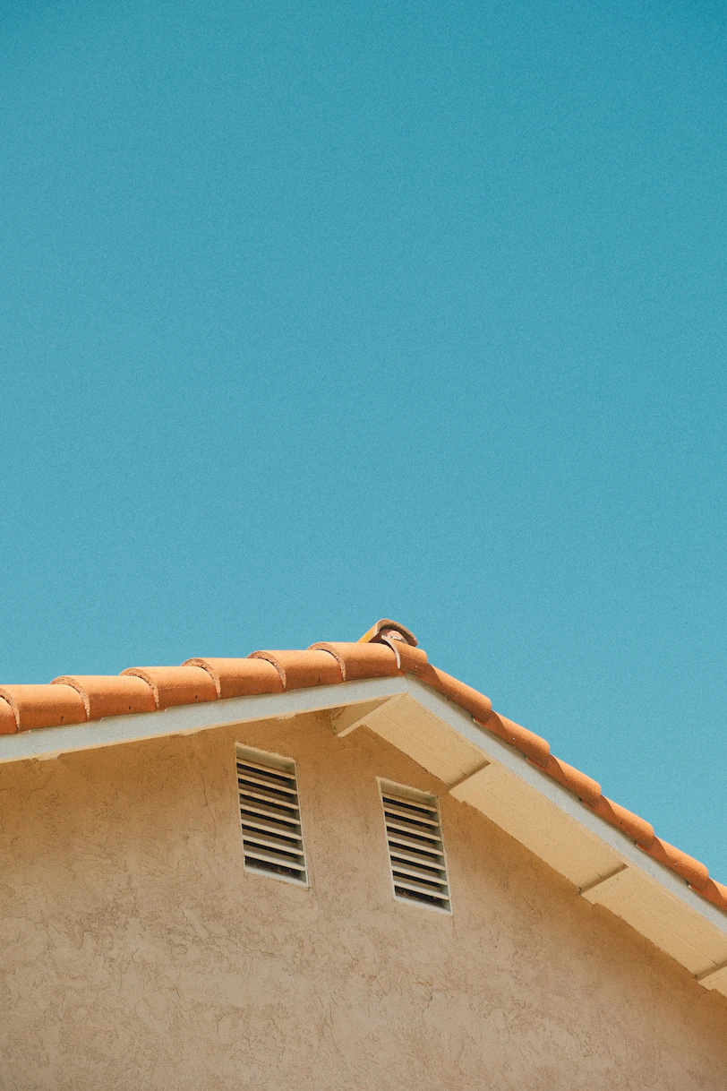 Building corner with orange roof tiles and clear blue sky.