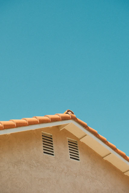 Building corner with orange roof tiles and clear blue sky.