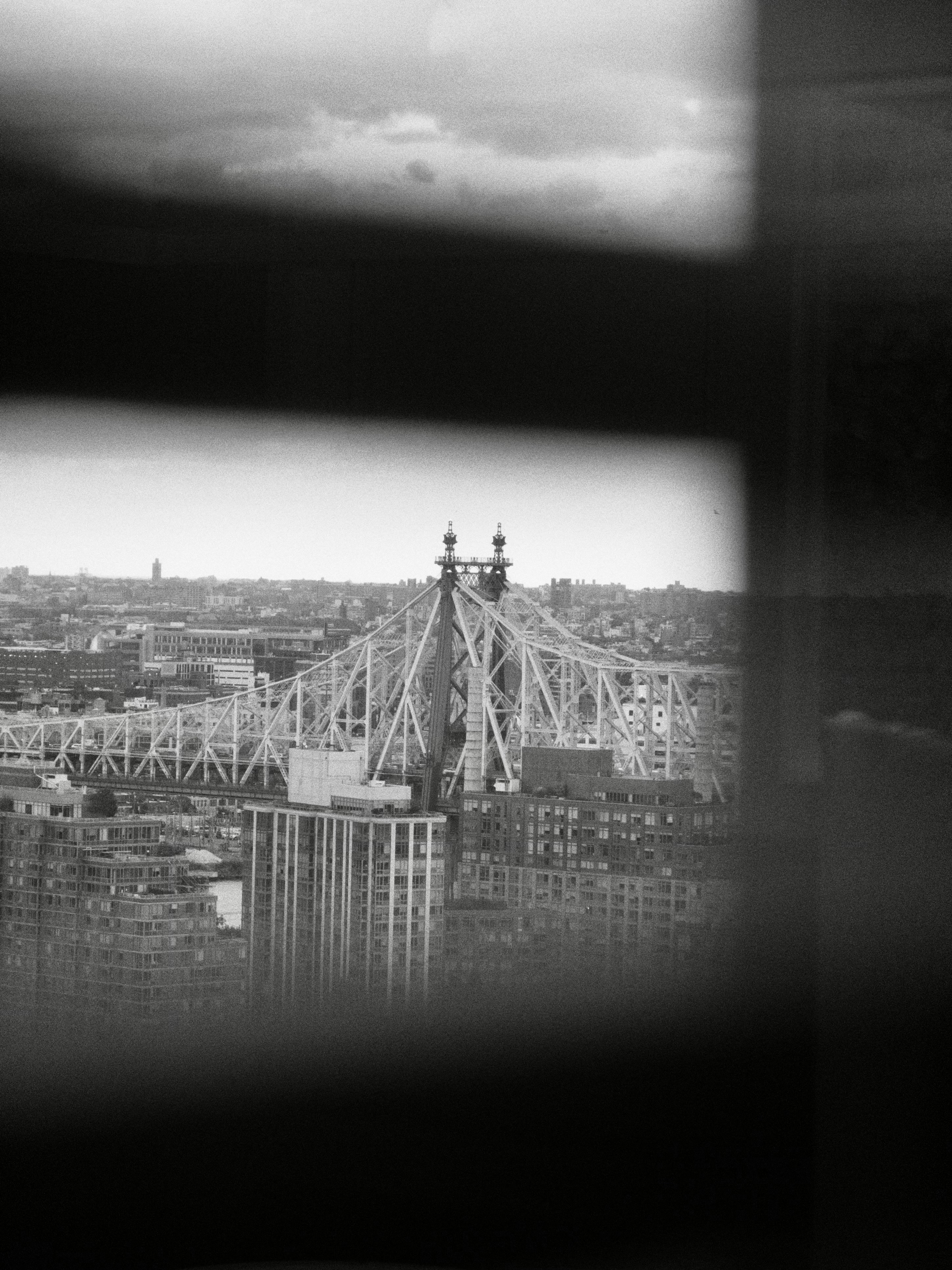 Black and white view of queensboro bridge and city buildings.
