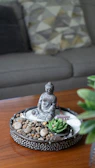 Miniature zen garden with buddha statue on wooden table.