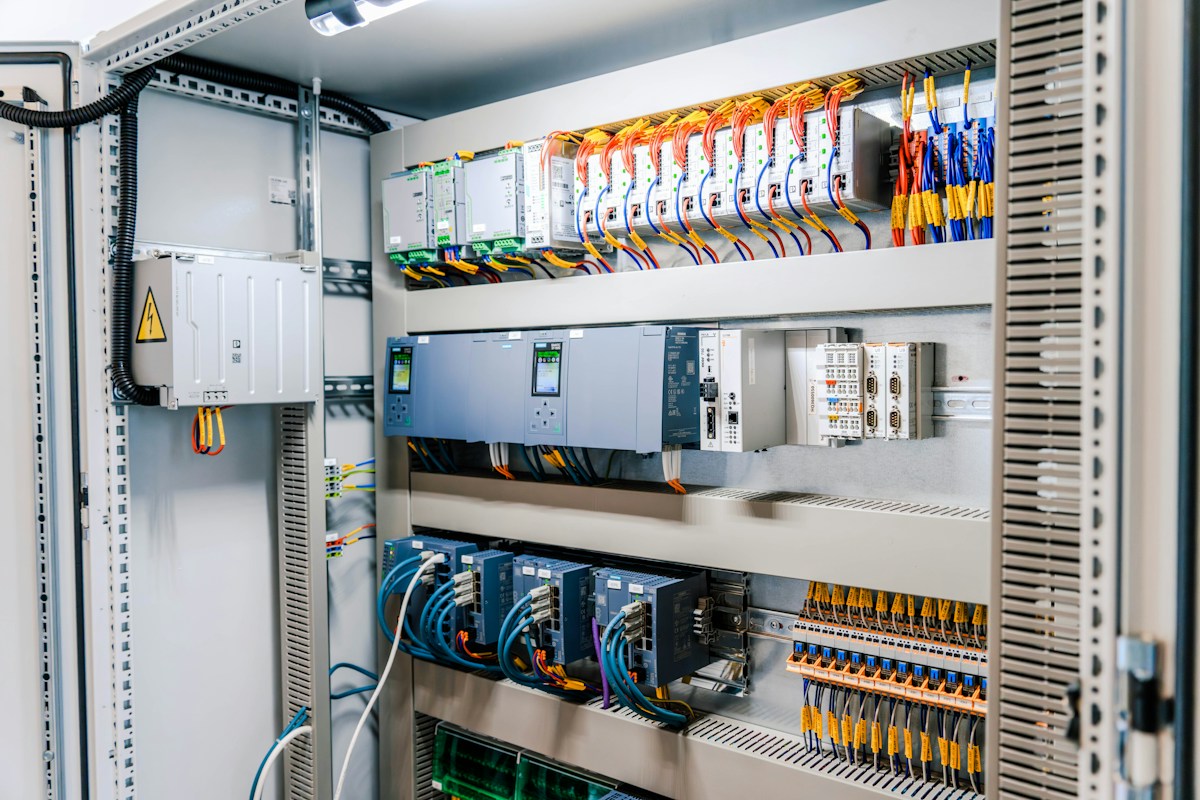 Painel elétrico industrial aberto, com cabos e módulos de controle