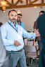 Bearded man in blue shirt gesturing while speaking indoors.
