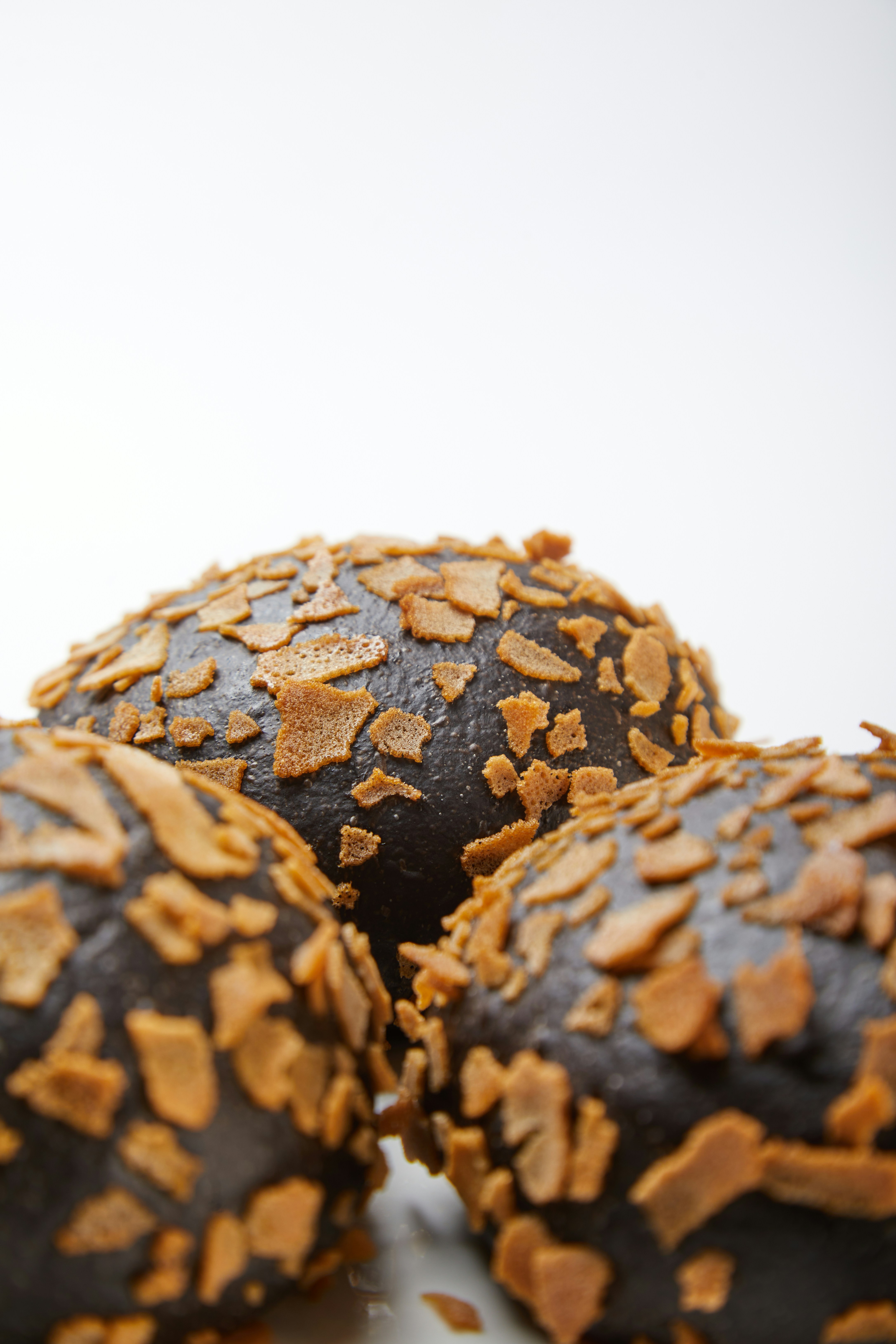 Drei dunkle Schokoladendesserts, überzogen mit goldenen Flocken.