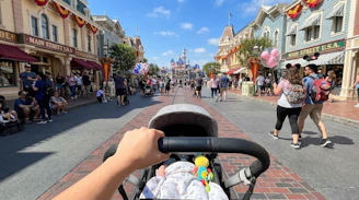 Pushing a baby stroller on a bustling theme park street.