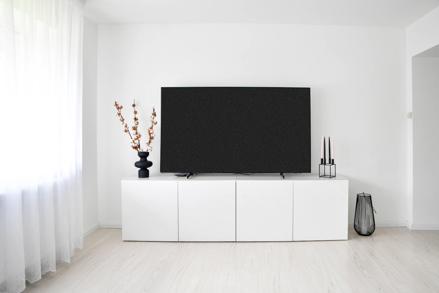 Minimalist white room with a television and storage cabinet