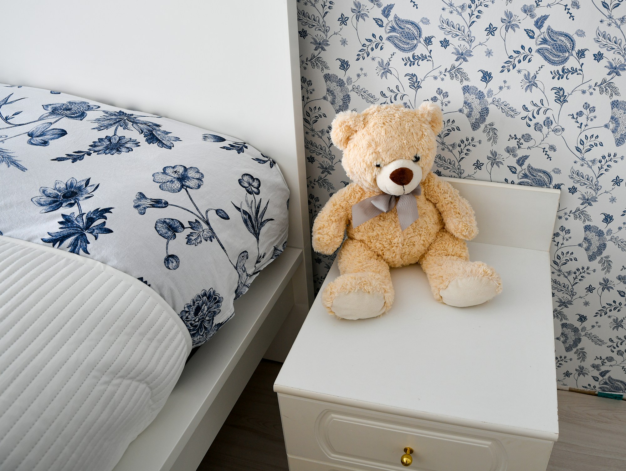 A teddy bear on a bedside table in a cozy vintage-inspired kids bedroom