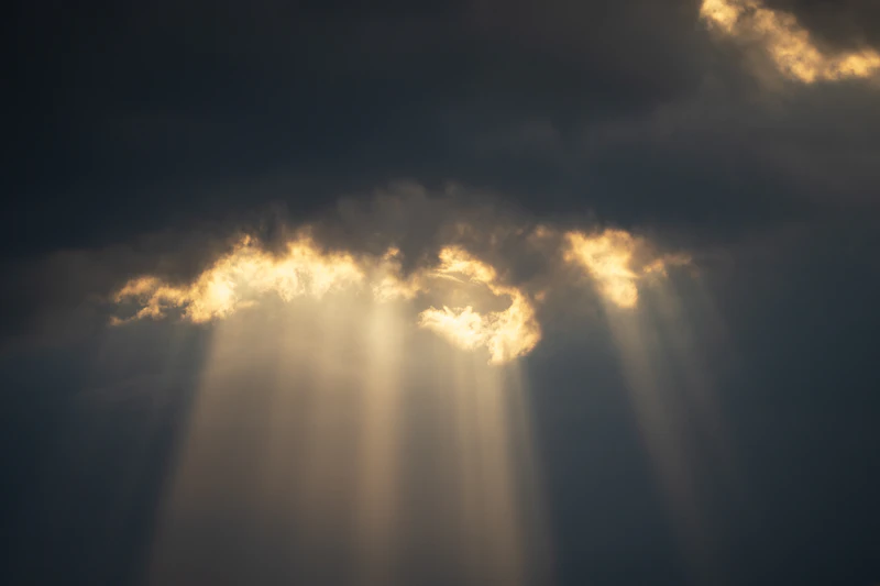 Sunlight breaking through dark storm clouds