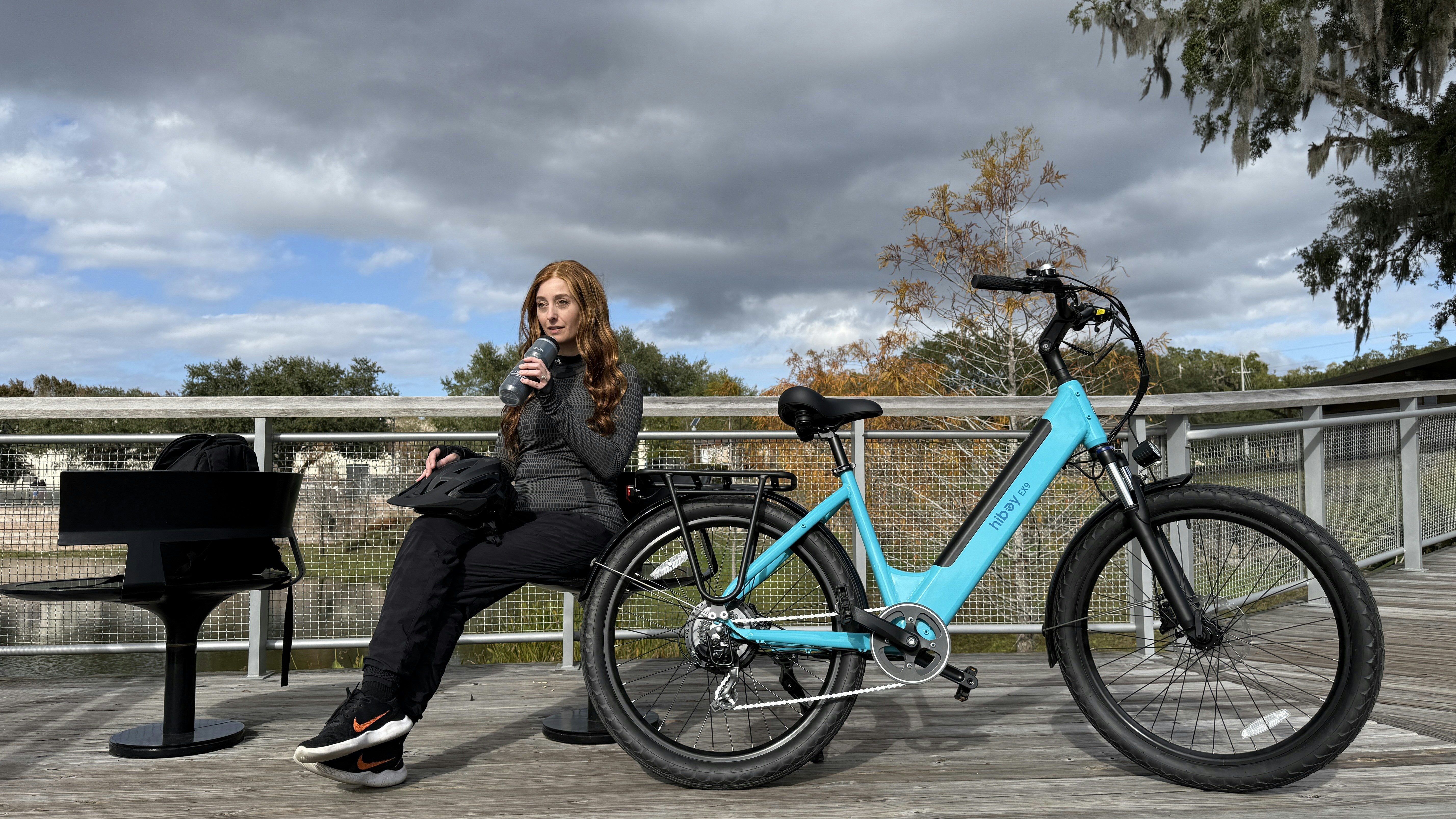 Woman sitting on a bench with a blue electric bicycle