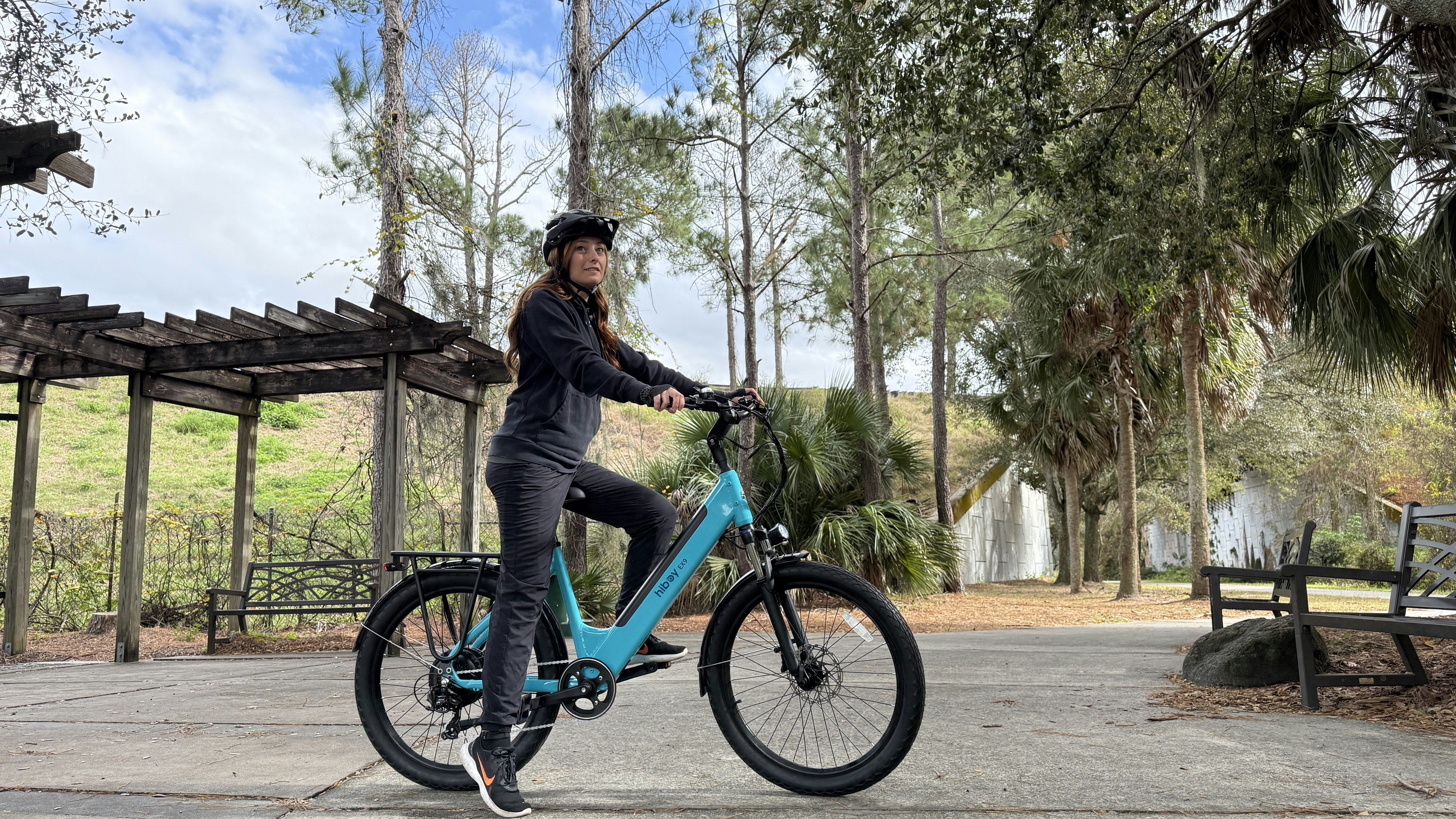 Woman with helmet and turquoise bicycle on a park path