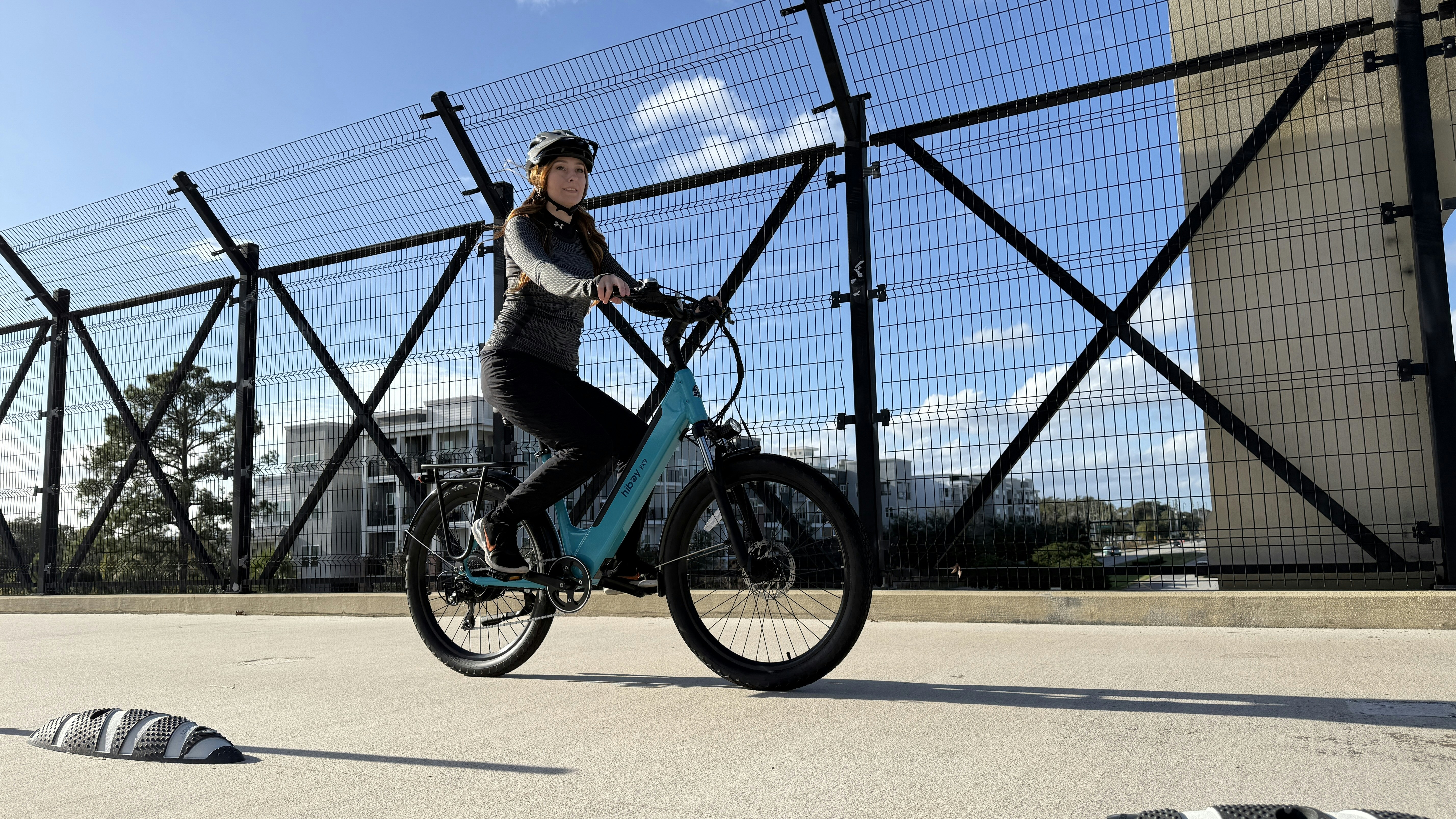 Woman riding a turquoise bicycle on an overpass