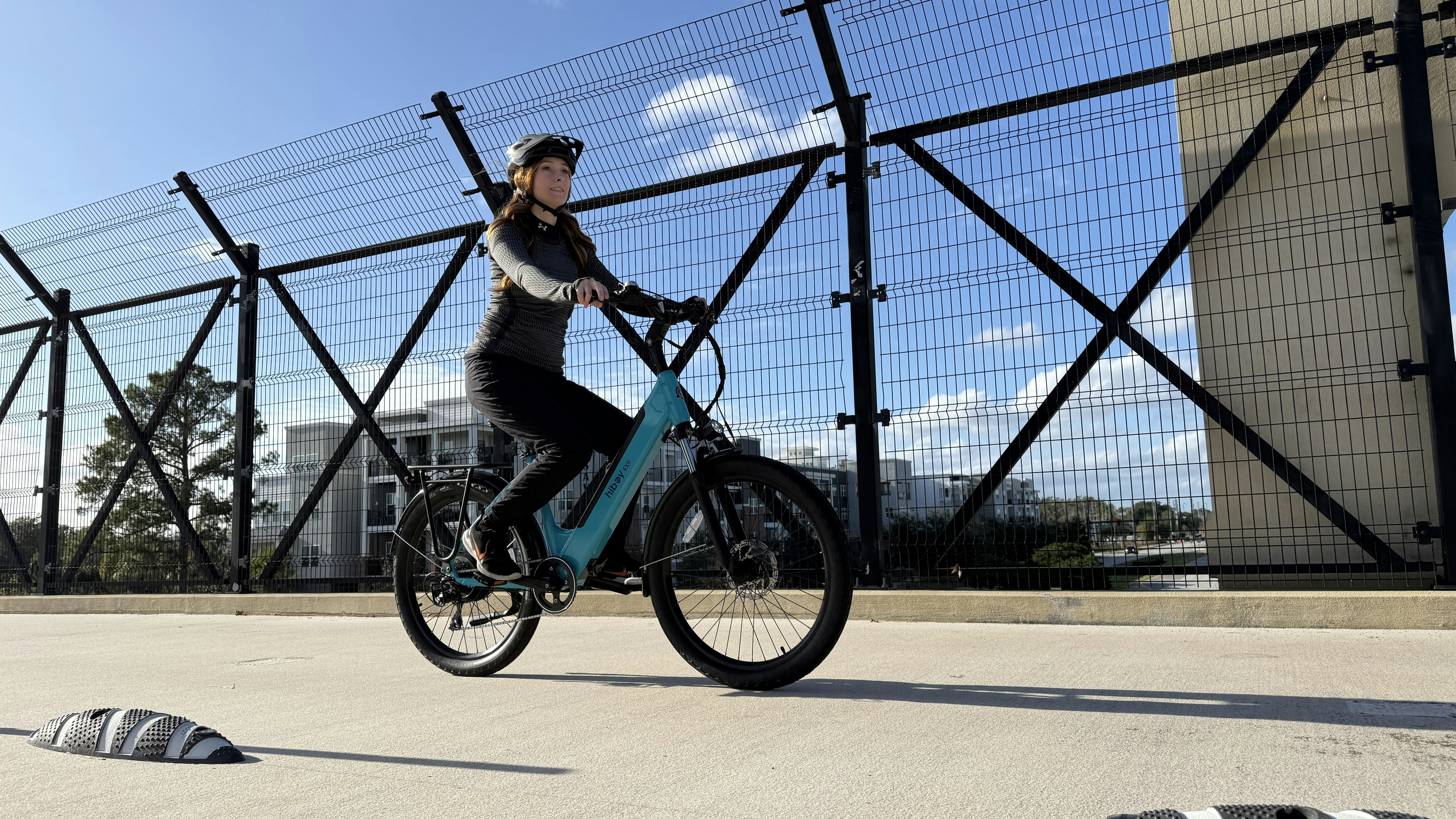 Woman riding a blue bicycle on a bridge