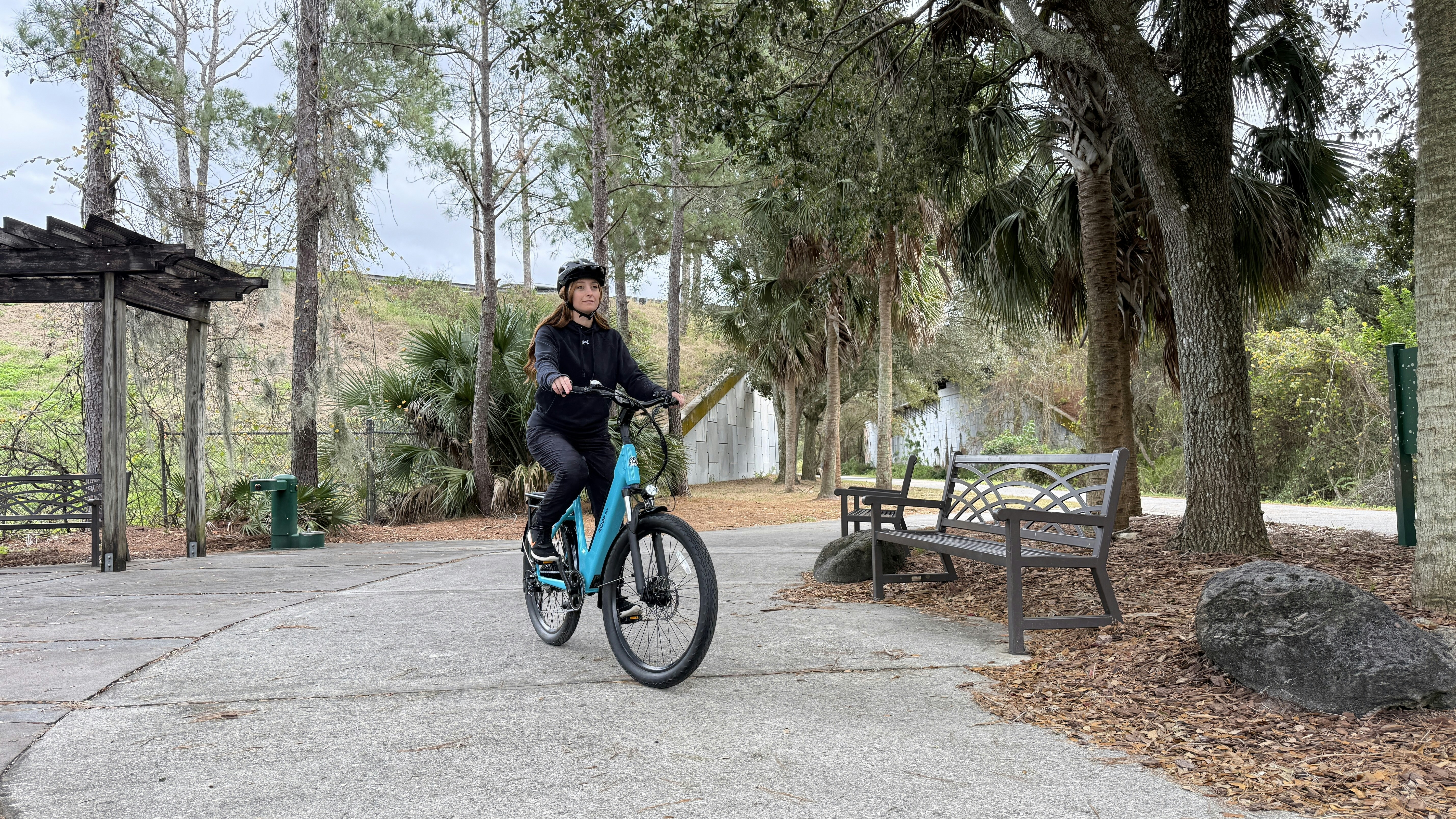 Woman riding a blue bicycle through a scenic park path
