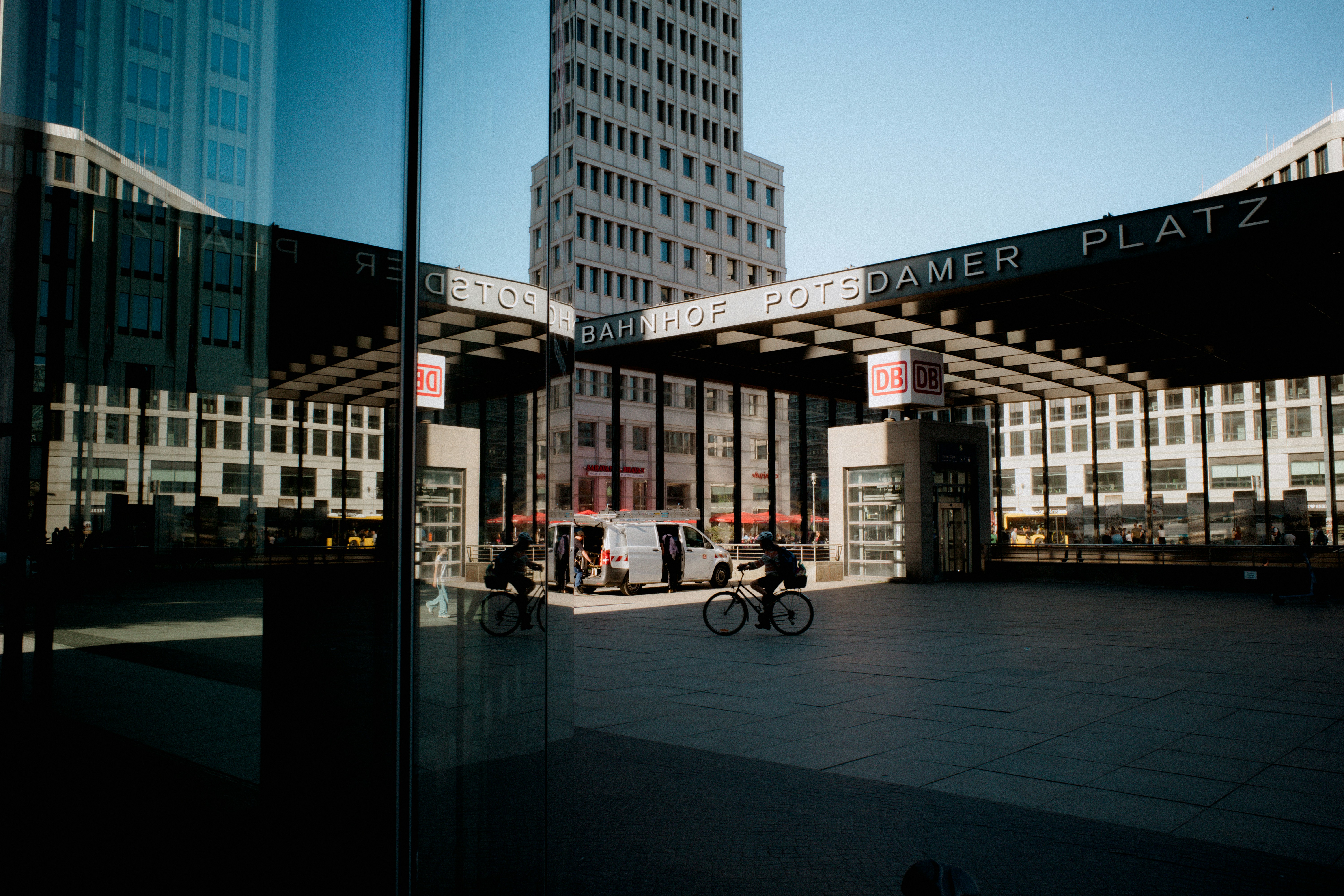 Bicyclists ride through a modern city square.
