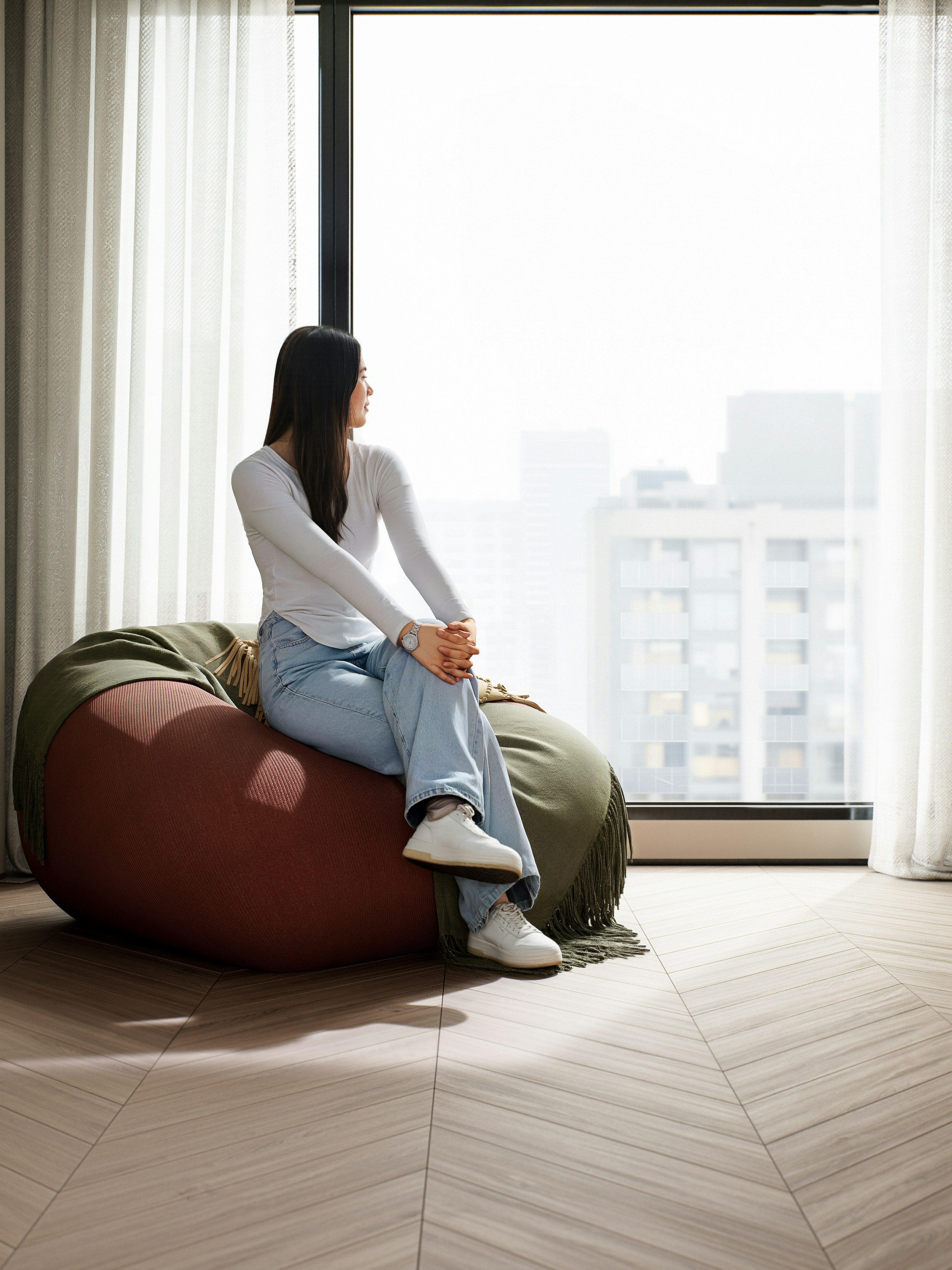 Woman sitting on a bean bag by a window