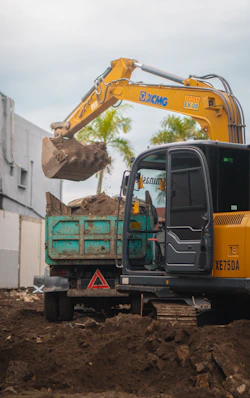 Yellow excavator moving soil into a dump truck